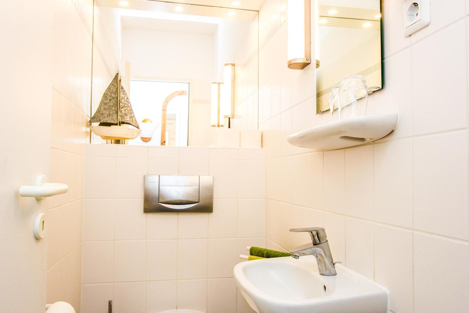 Badezimmer mit Waschbecken, Spiegel und Segelboot-Dekoration.