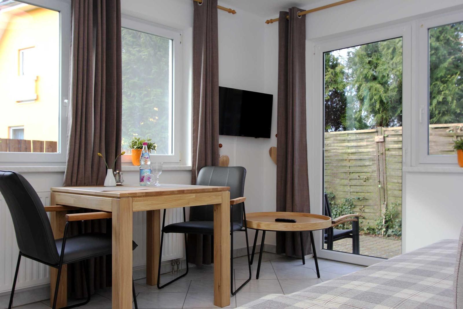 Essbereich mit Tisch, Stühlen und Fernseher. Durchgang zur Terrasse mit Gartenblick.