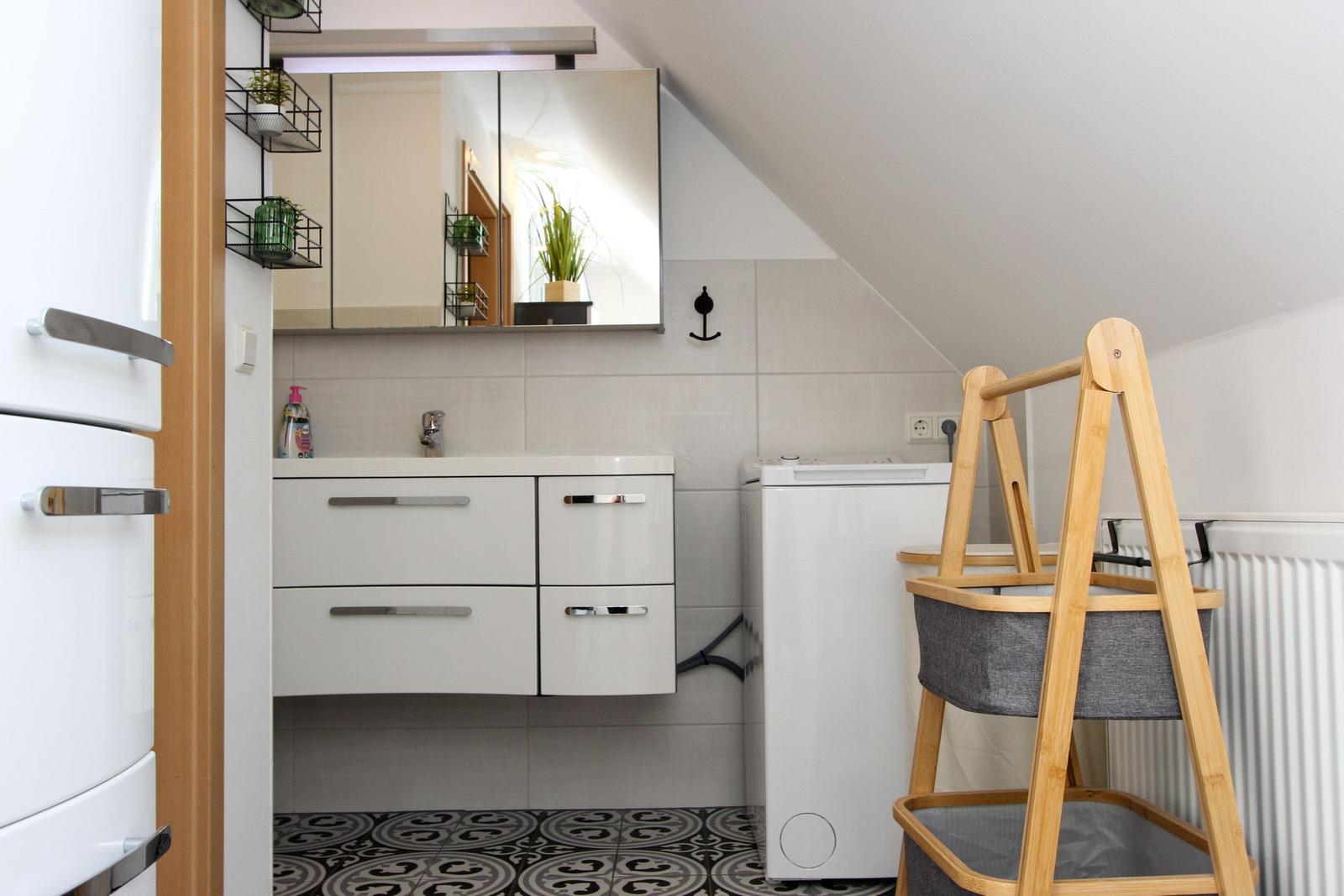 Waschraum mit Spiegelschrank, Waschmaschine und Badezimmermöbel.