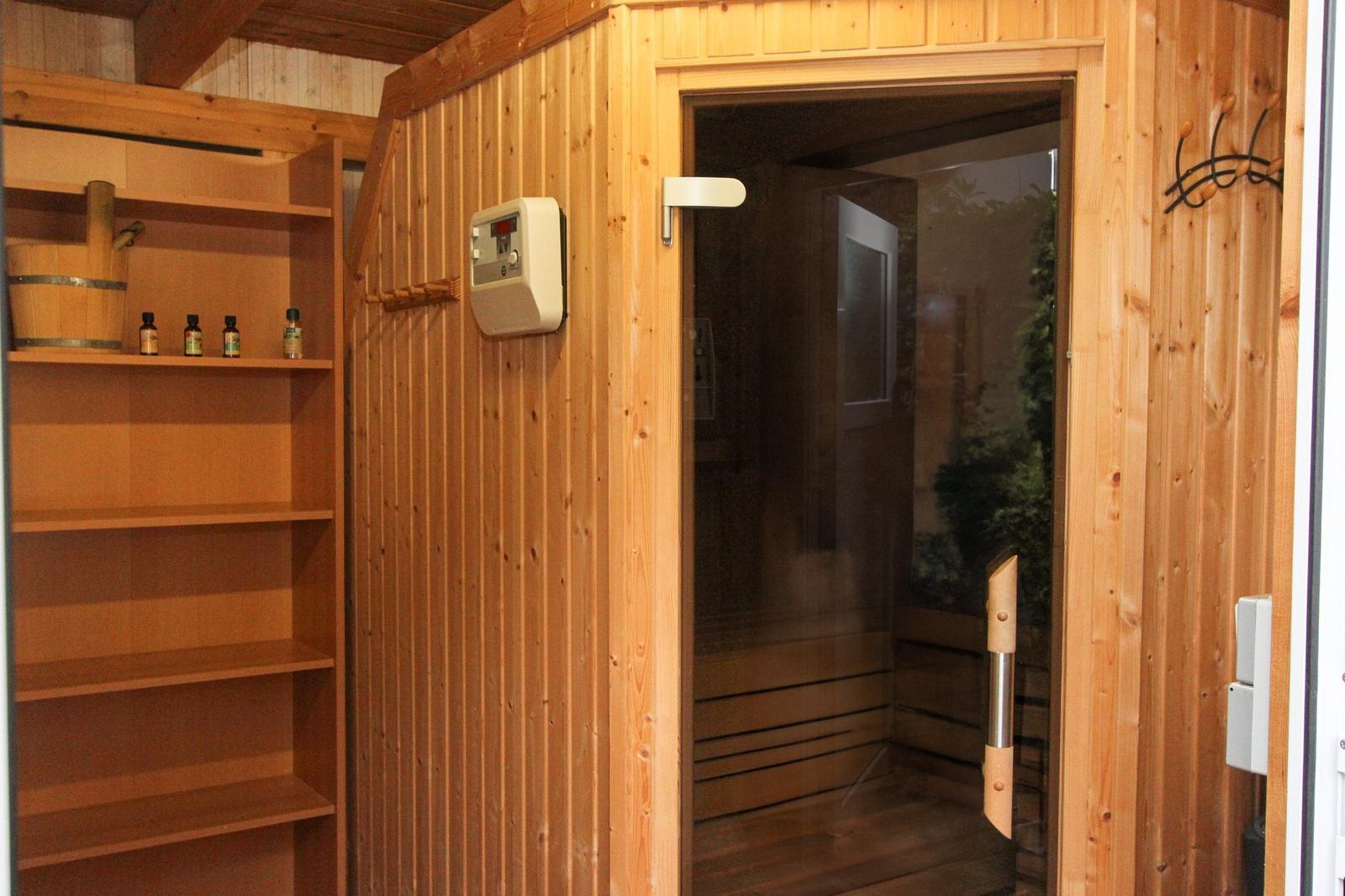 Holzsauna mit Glasfront und Regal mit Öle.