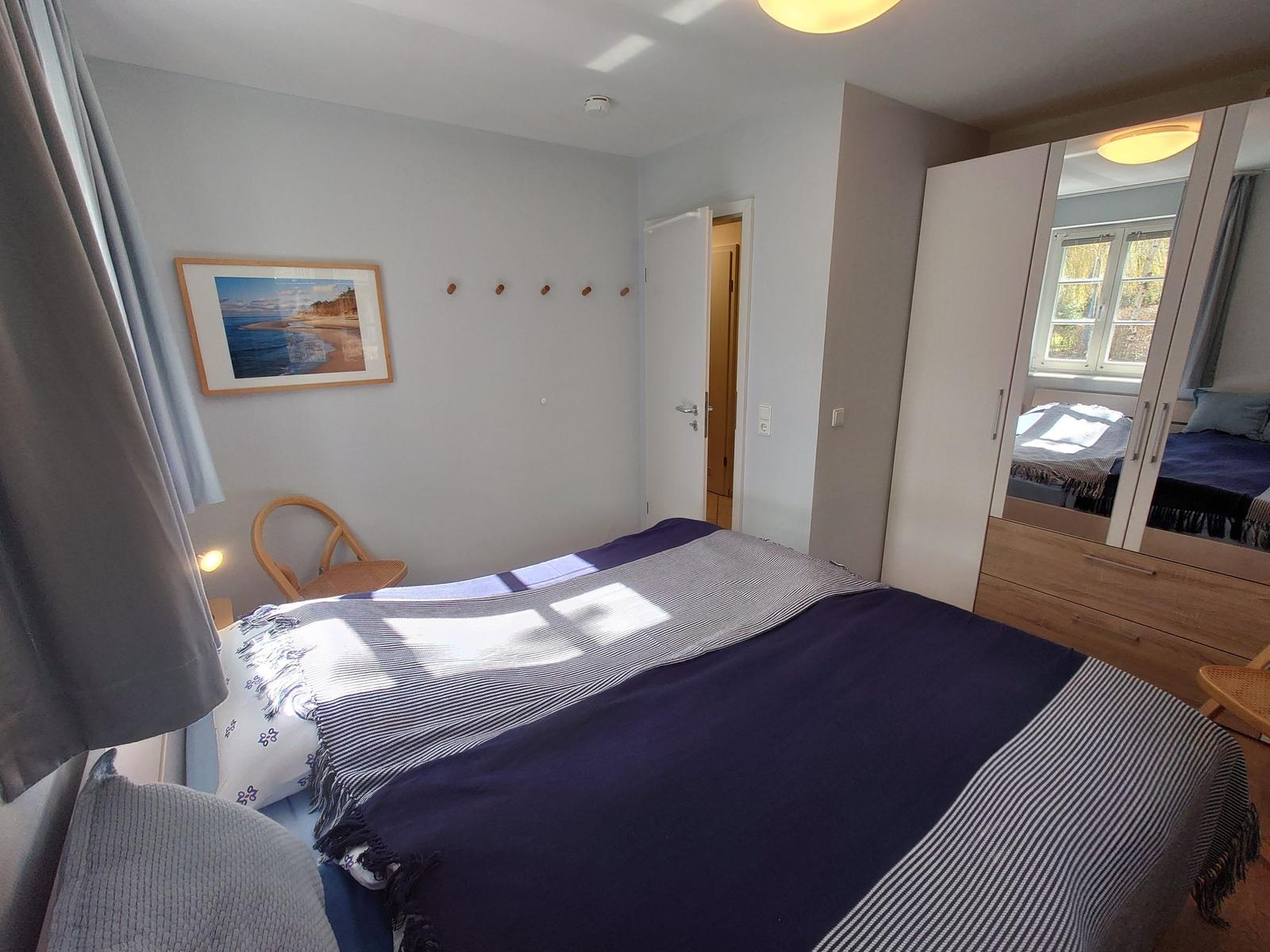 Schlafzimmer mit Bett, Kleiderkabine und Wandbild