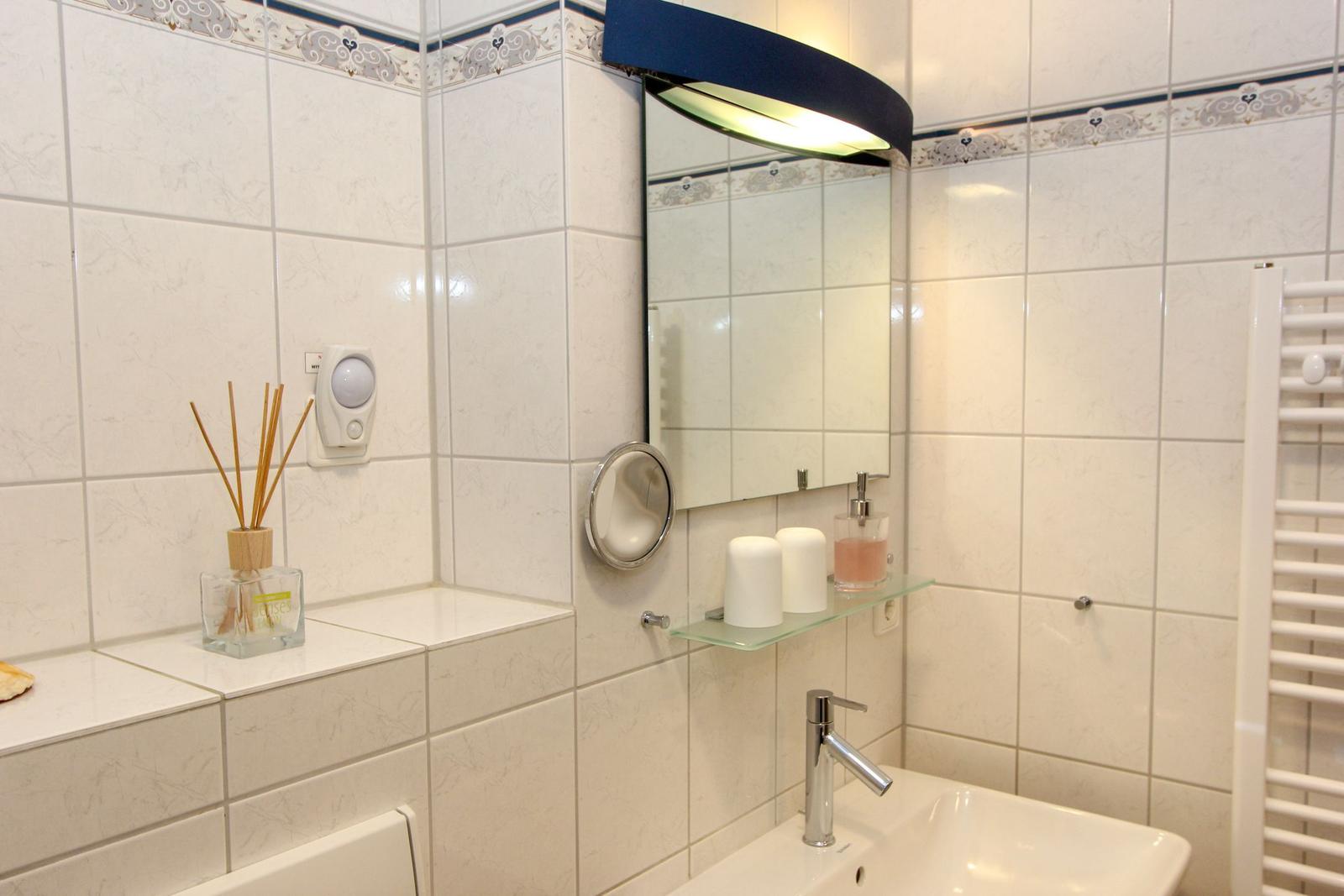 Badezimmer mit Spiegel, Waschbecken und Heizkörper an der Wand.
