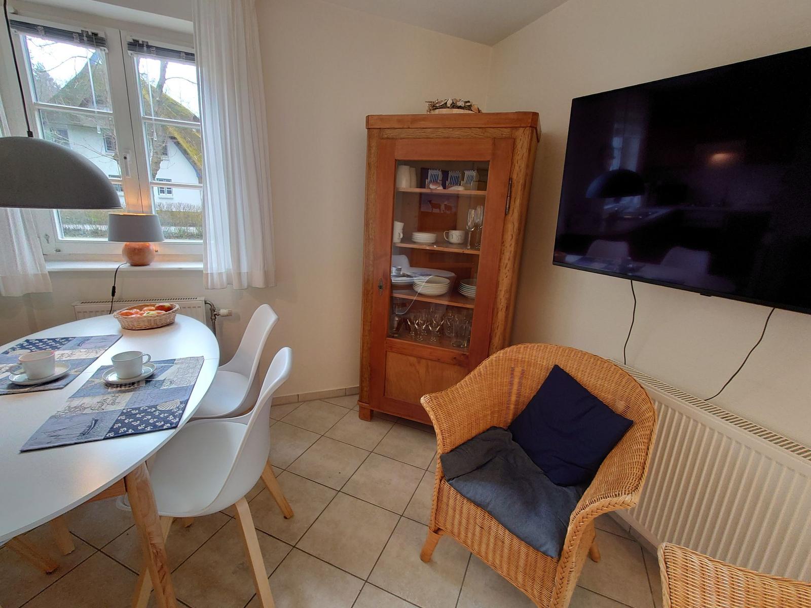 Esszimmer mit Tisch, Stühlen, TV und Holzschrank.