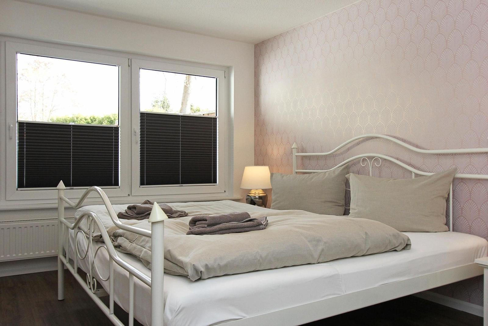 Schlafzimmer mit Bett, Fenster und Tapete an der Wand.