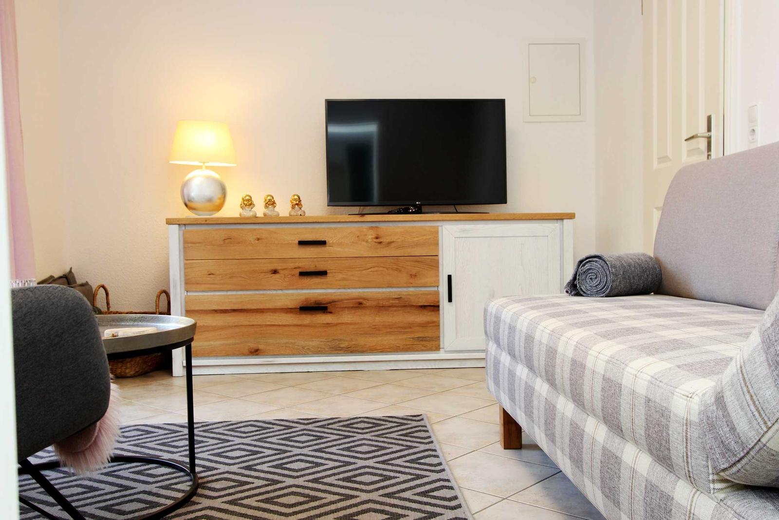 Wohnzimmer mit Sofa, TV-Boden und Beleuchtung.