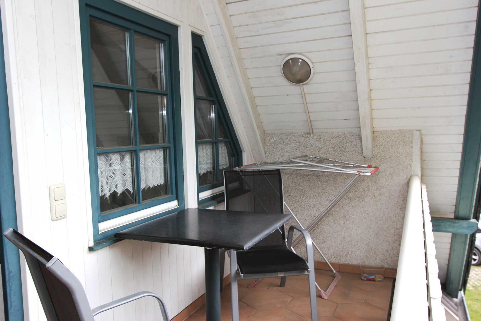 Terrasse mit Tisch, zwei Stühlen und Wäscheständer an der Wand.