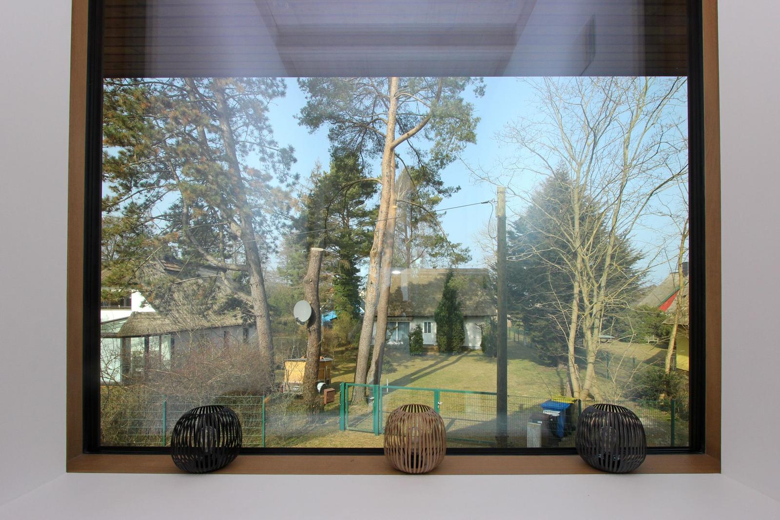 Durch das Fenster ist ein Garten mit Bäumen und einem Haus im Hintergrund sichtbar.