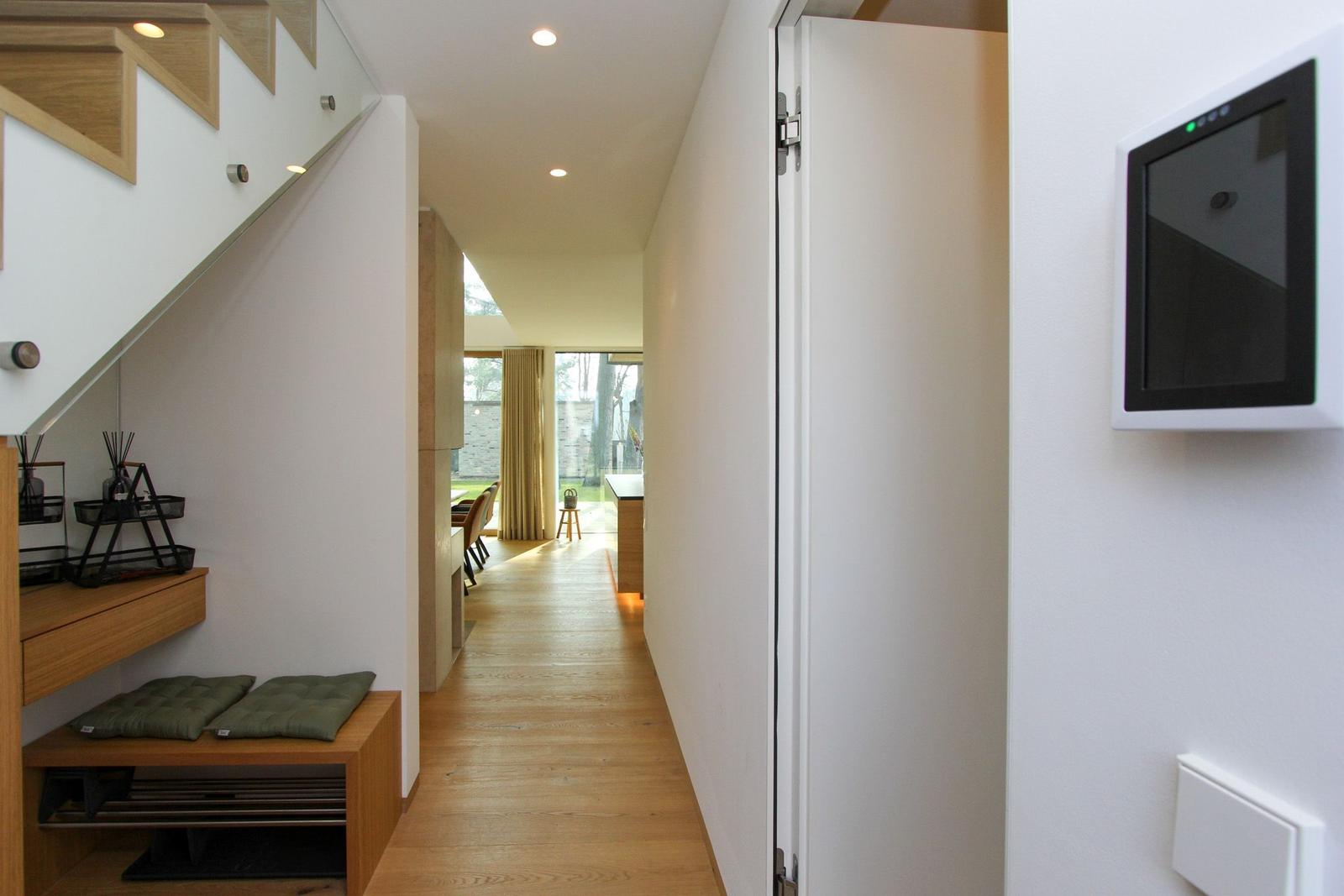 Flur mit Holzboden, Treppenhaus und Fernsehgerät an der Wand.