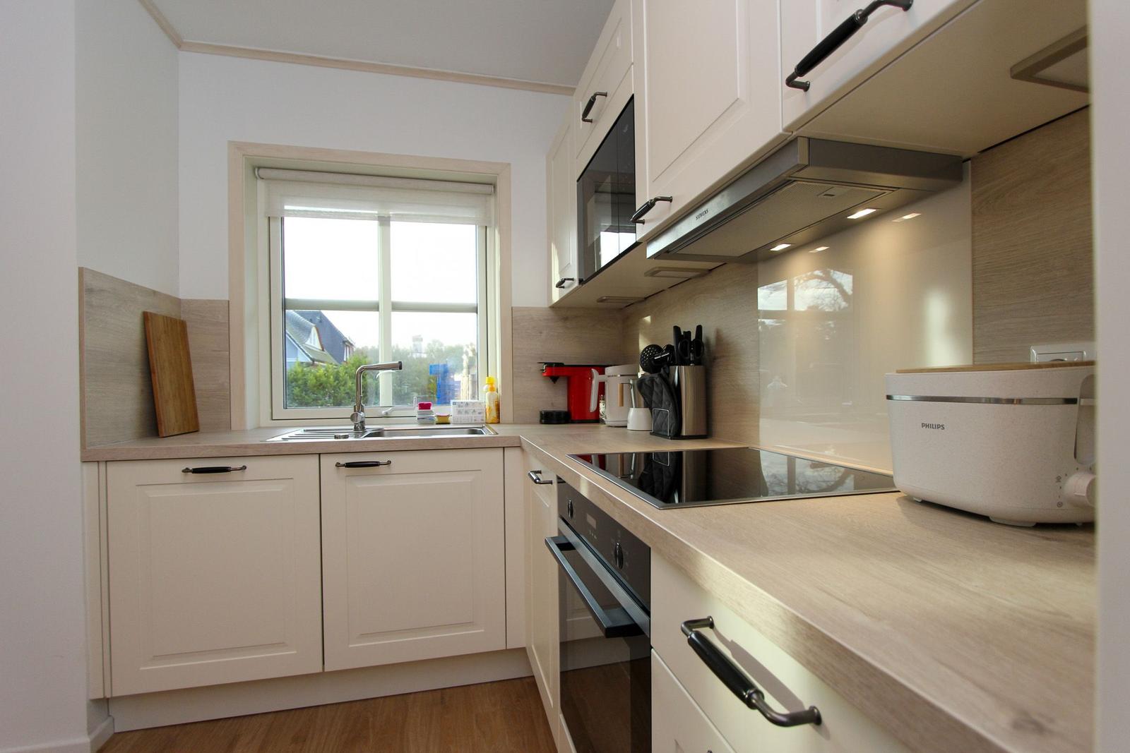 Küche mit weißen Schränken, Holzwerkzeug und Fenster mit Blick nach draußen.