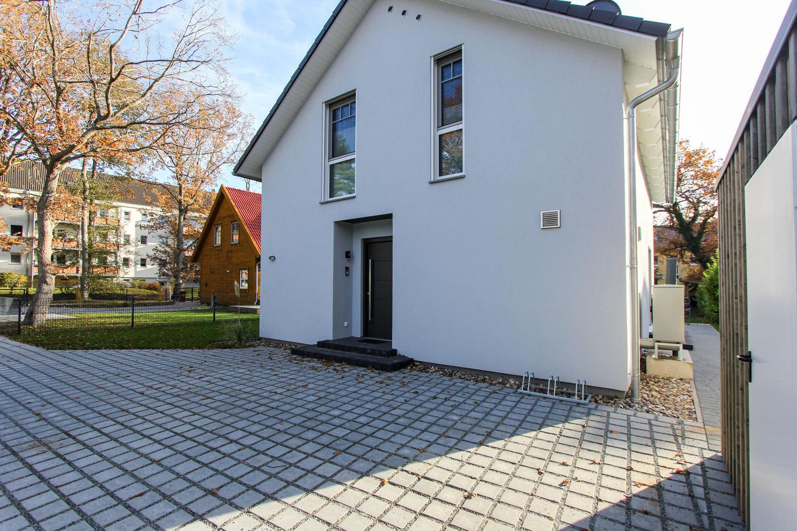 Moderne weiße Villa mit Eingangstür und gepflastertem Hof.