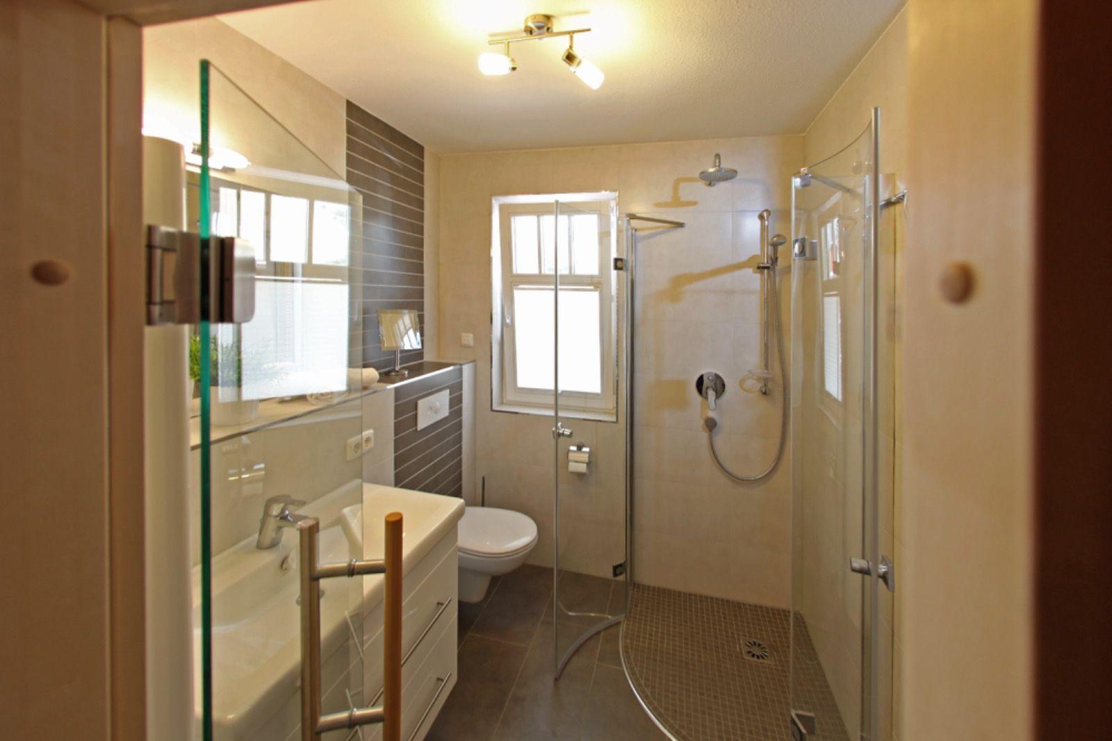 Badezimmer mit Dusche, WC und Waschbecken. Fenster sorgt für Tageslicht.