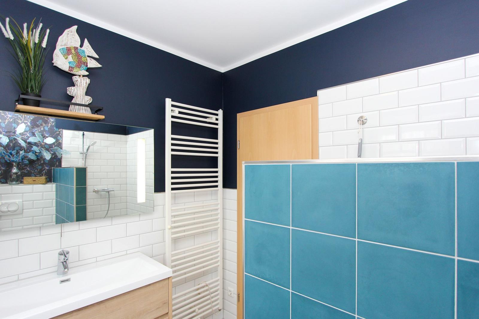 Badezimmer mit blauen Wänden, weißer Fliesenwand und Holzwaschbecken.