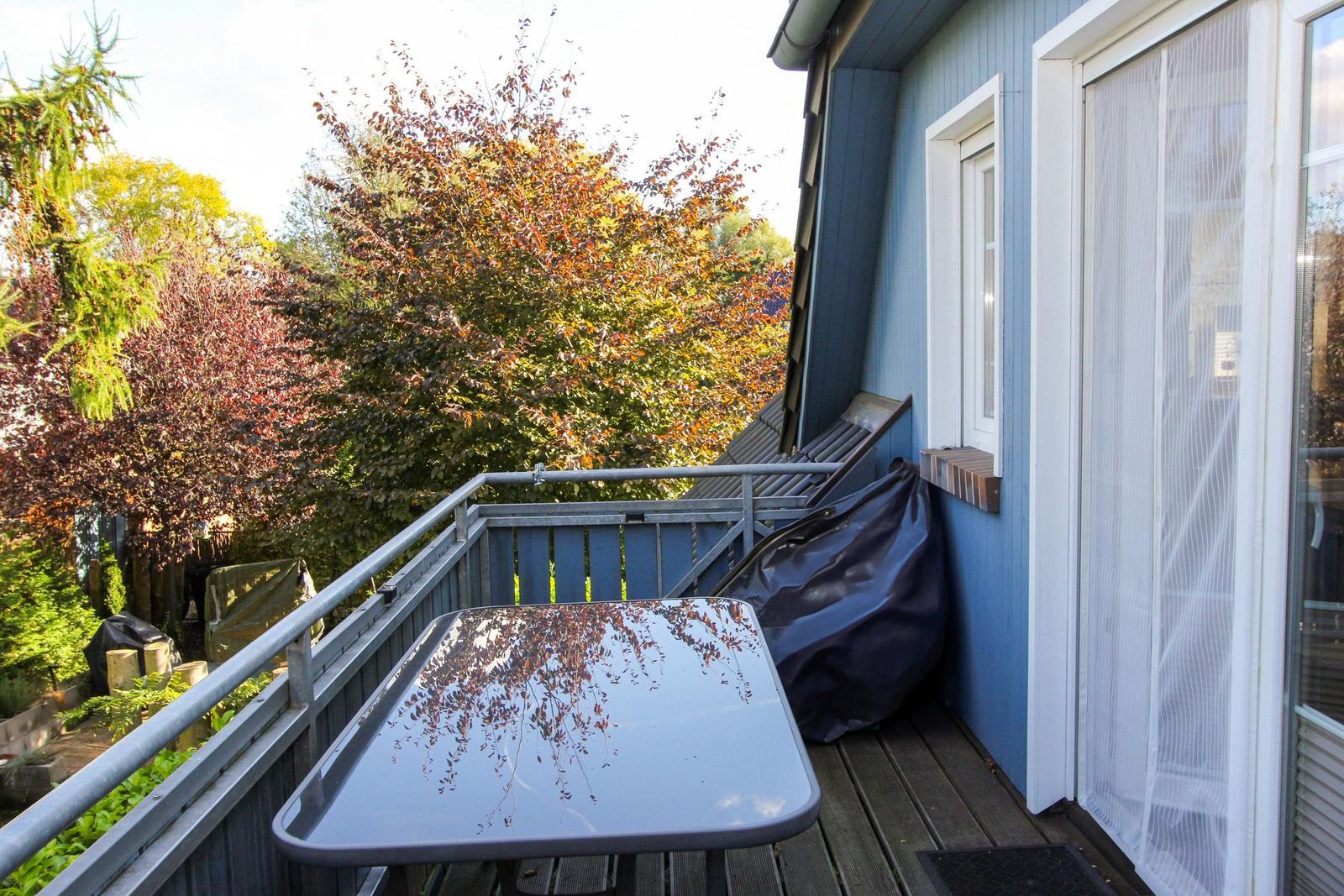 Terrasse mit Tisch, Gartenblick und blauem Haus
