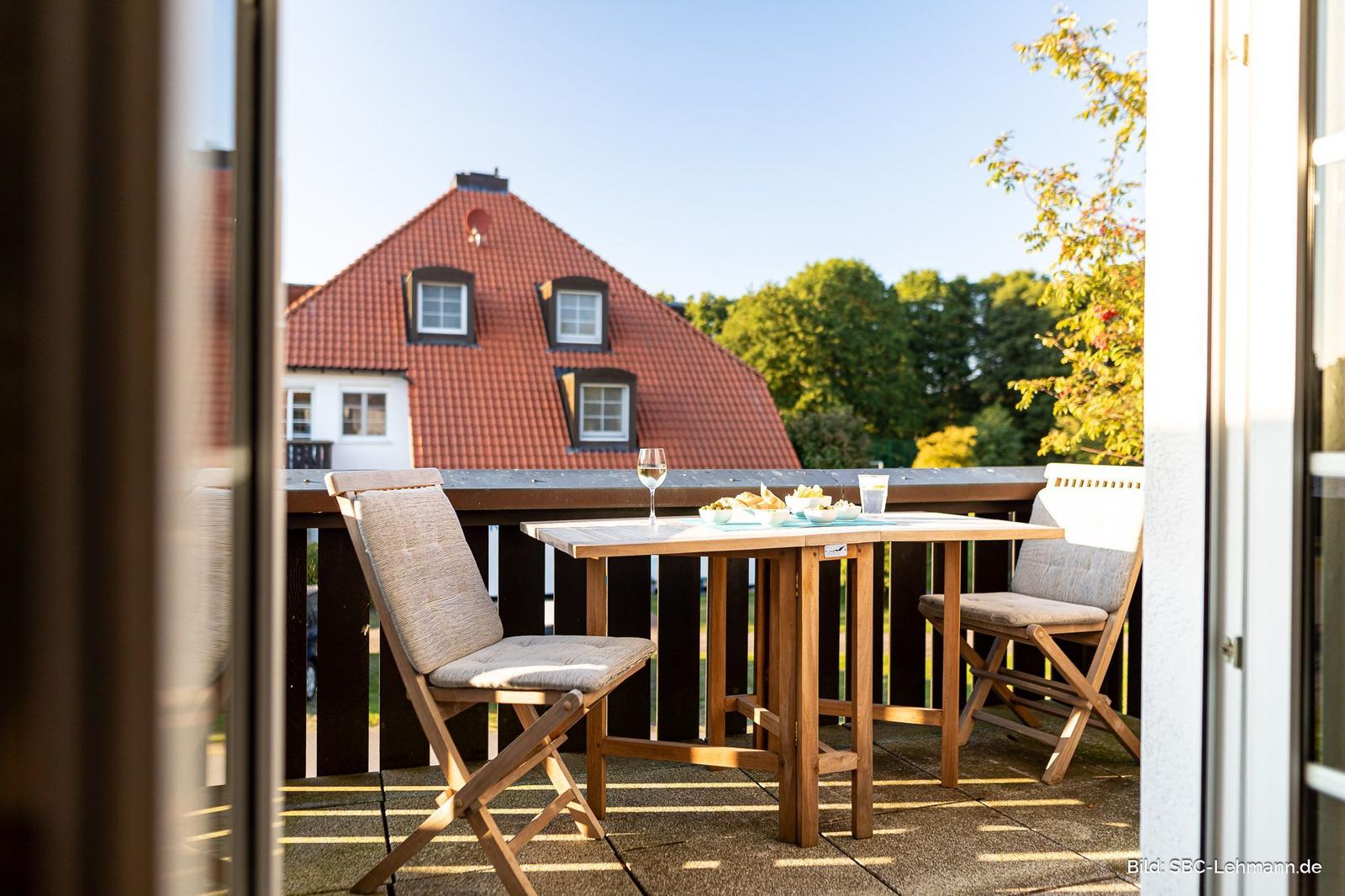 Terrasse mit Tisch und zwei Stühlen, Blick auf ein Haus mit rotem Dach.