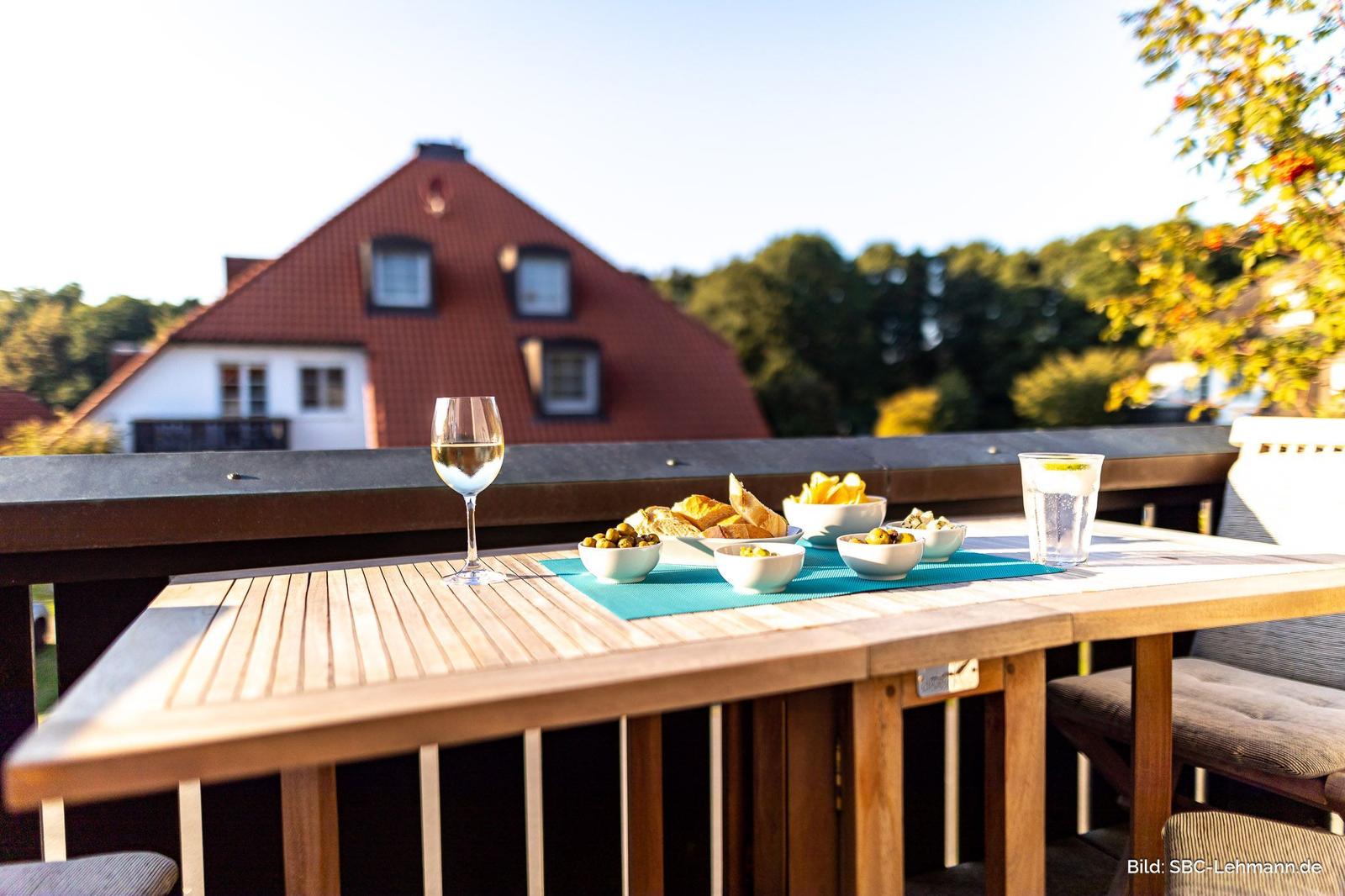 Tisch auf Terrasse mit Getränken und Snacks, Blick auf Haus und Bäume.