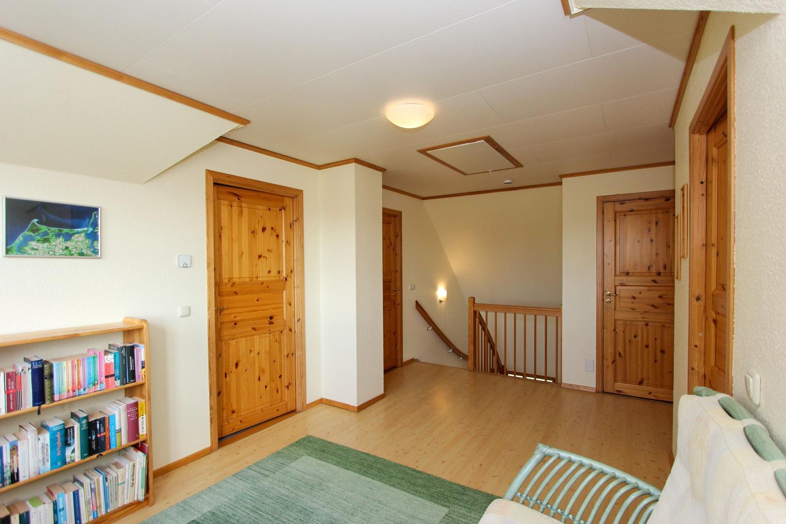 Wohnbereich mit Bücherregal, Holztreppe und mehreren Türen.
