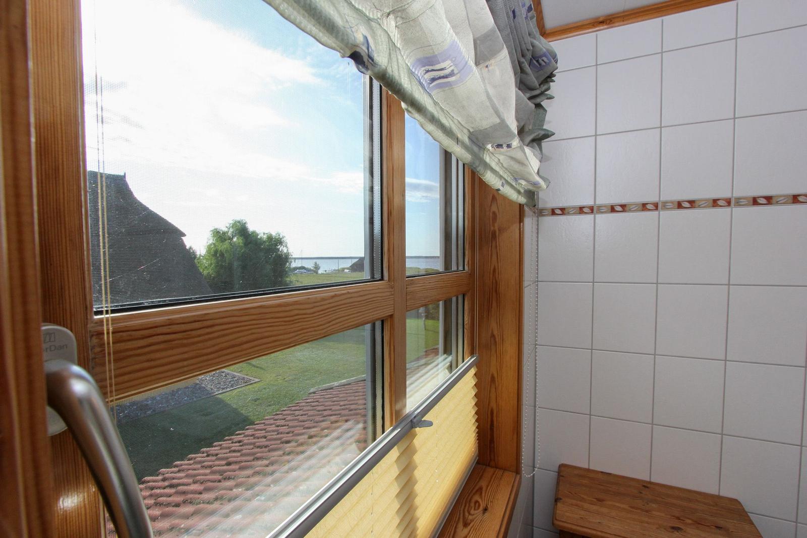 Badezimmer mit Holzfenster, Blick auf Dach und Grünfläche