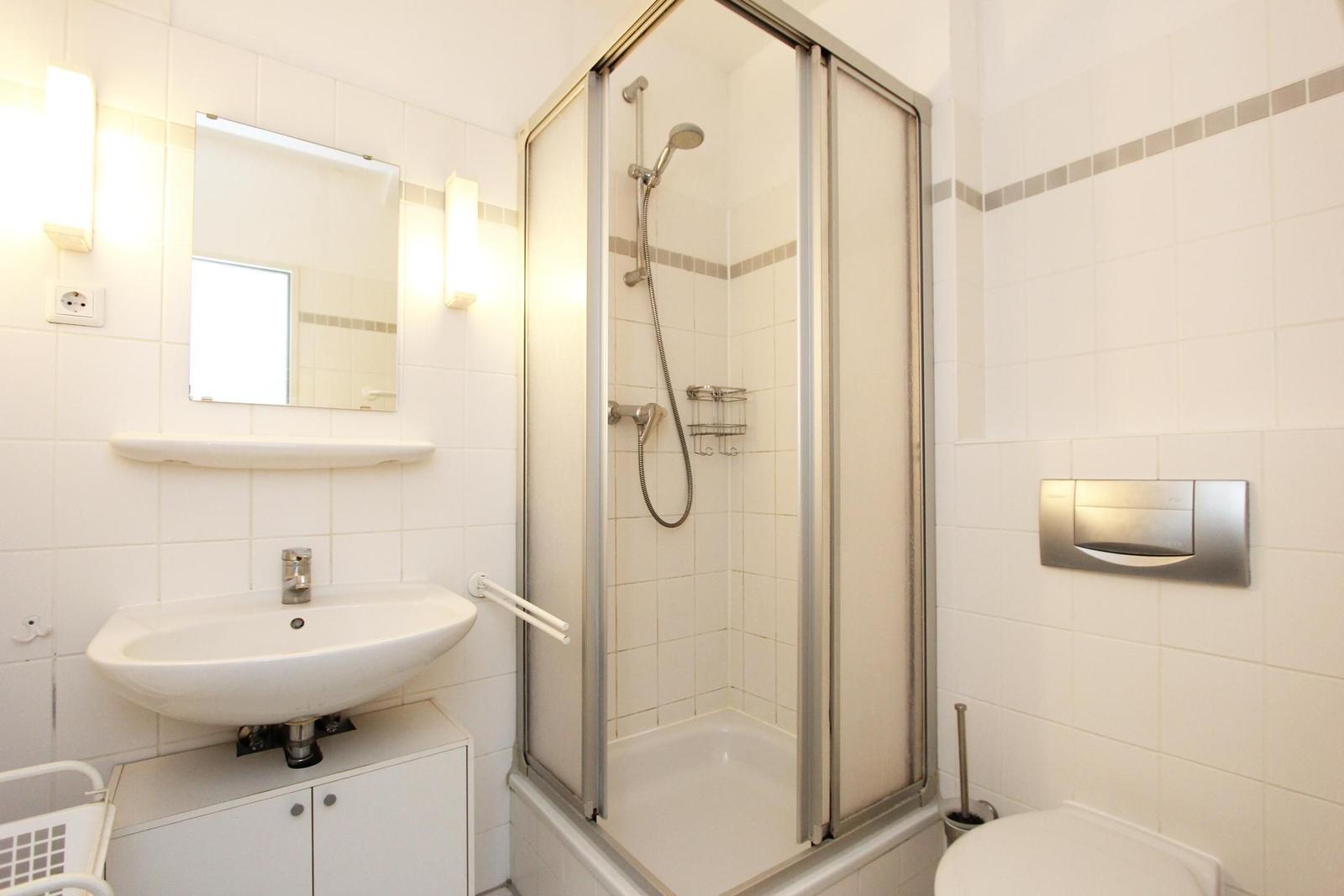 Badezimmer mit Dusche, Waschbecken und Toilette.