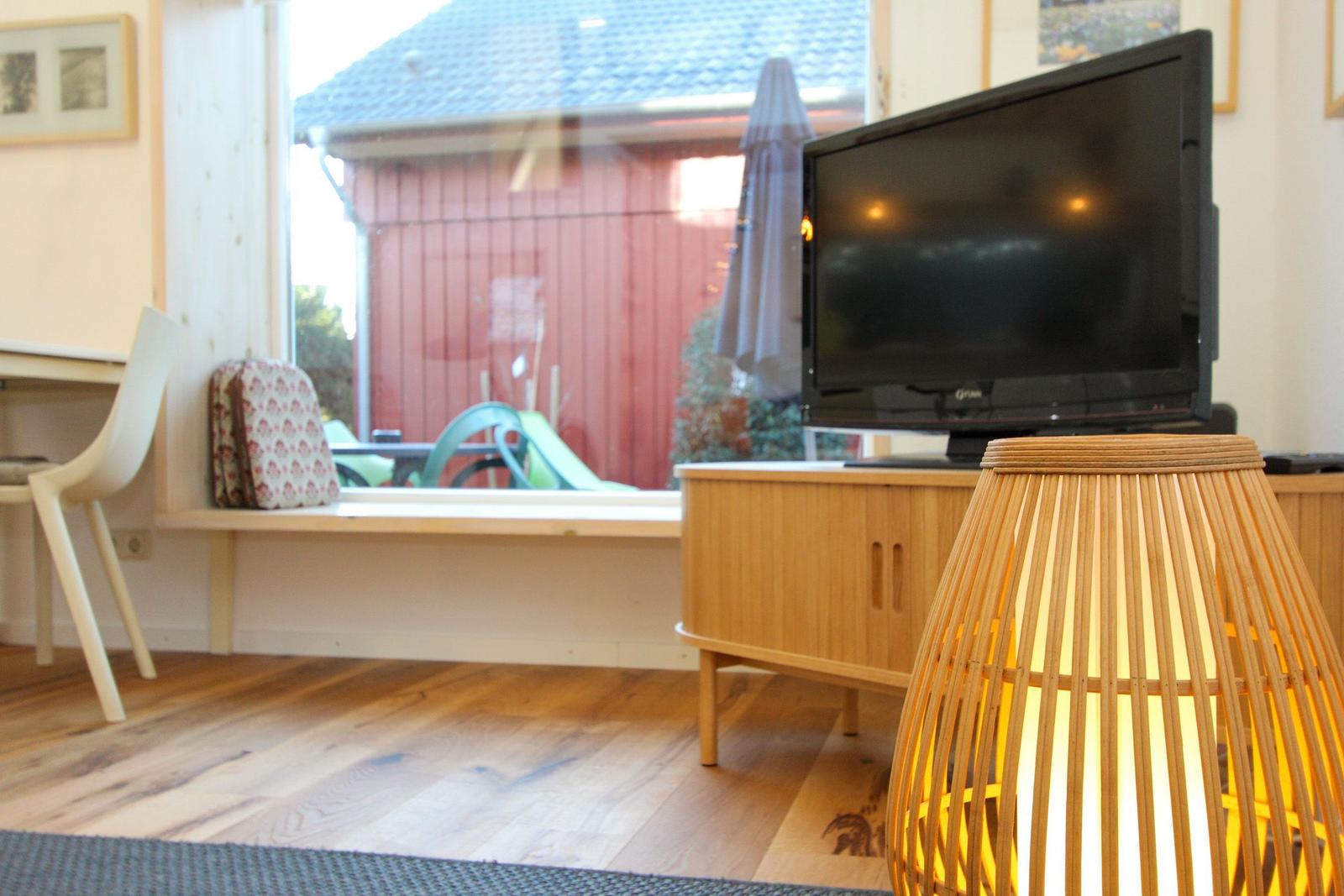 Wohnzimmer mit TV, Holzboden und Fensterblick auf Garten