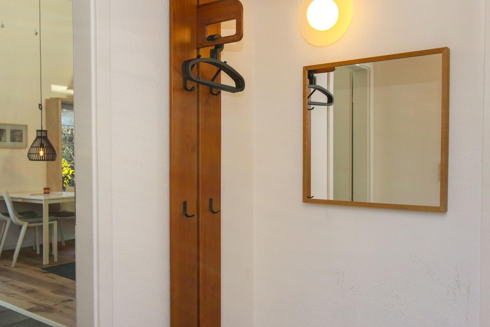 Hinter dem Eingangsbereich befindet sich ein Spiegel und ein Kleiderständer mit Haken.