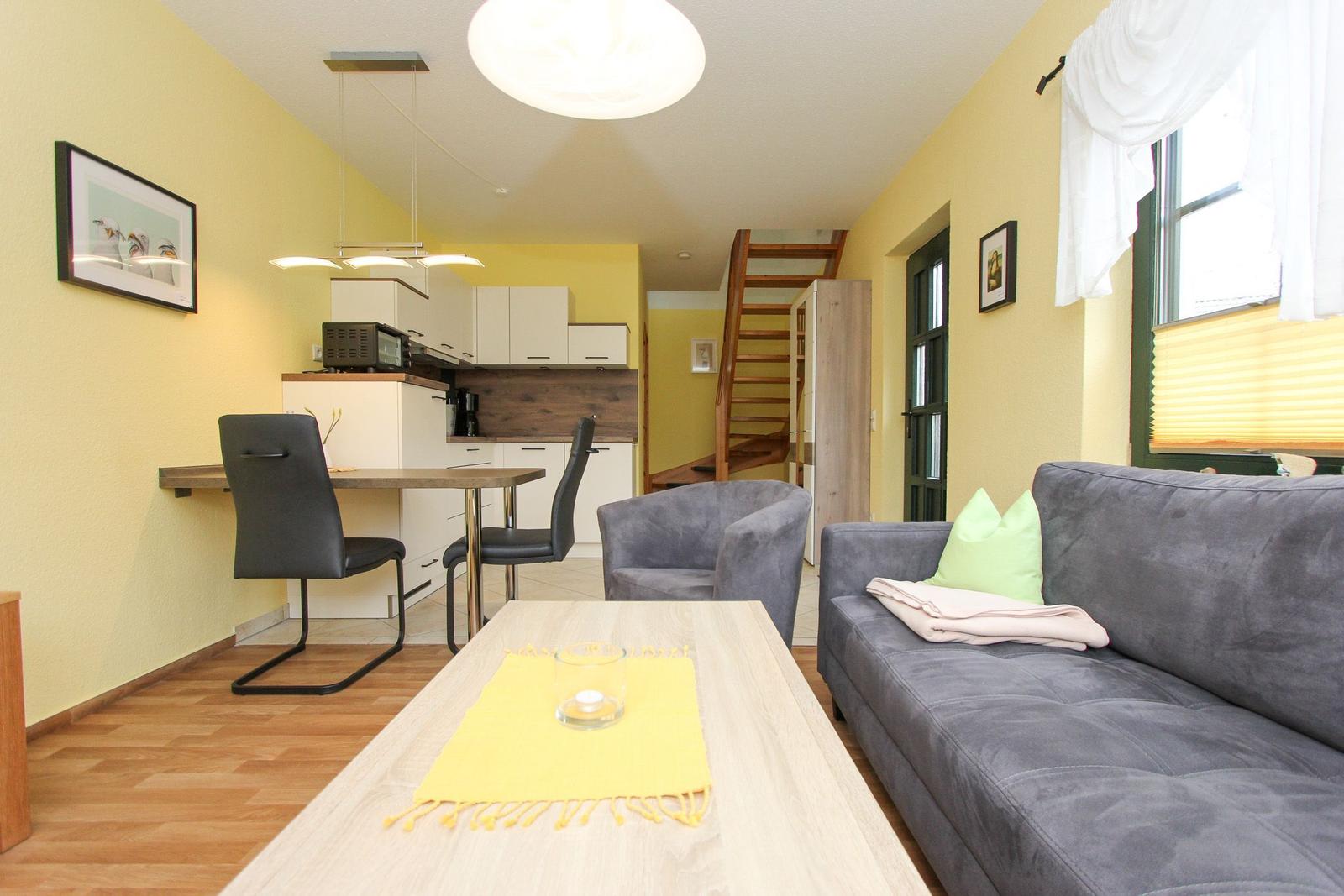 Wohn- und Essbereich mit Küchenzeile, Sofa und Stufen zur oberen Etage.