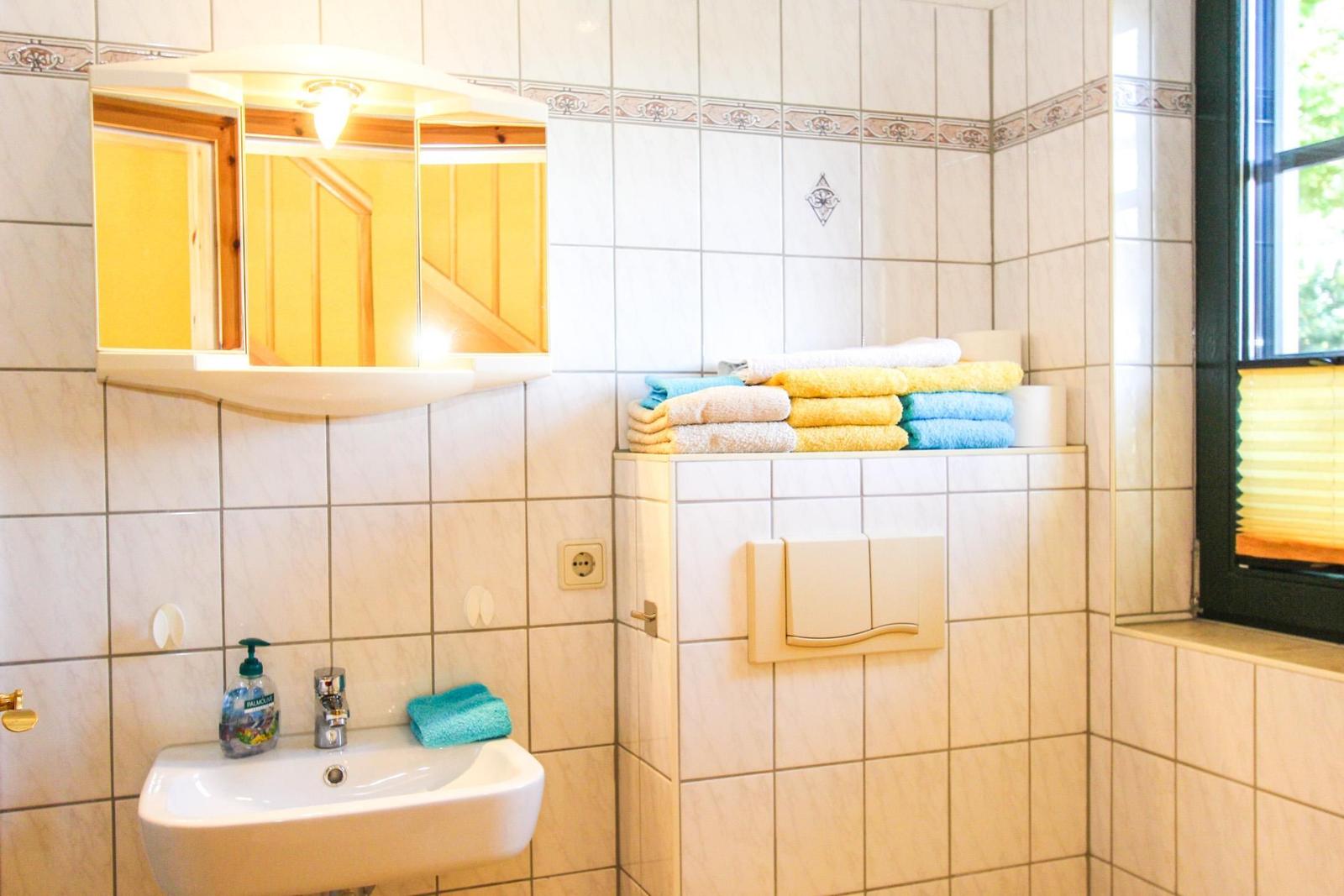 Badezimmer mit Waschbecken, Spiegelschrank und gefalteten Handtüchern.