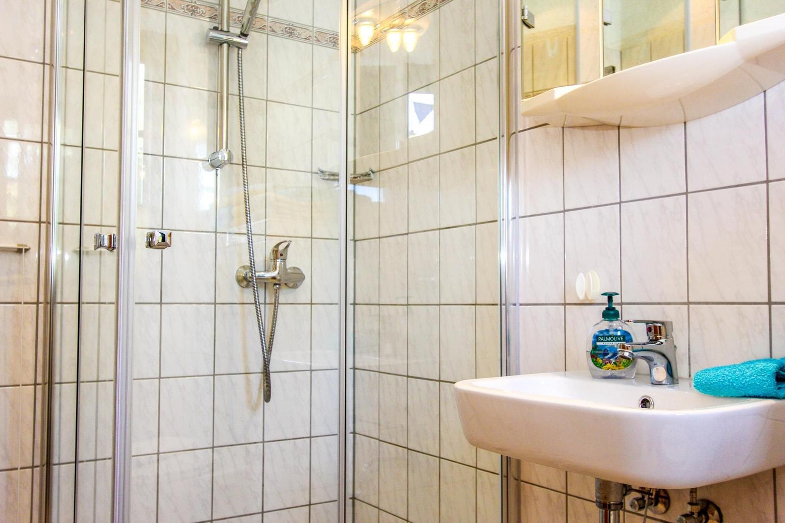 Badezimmer mit Dusche, Waschbecken und Spiegel