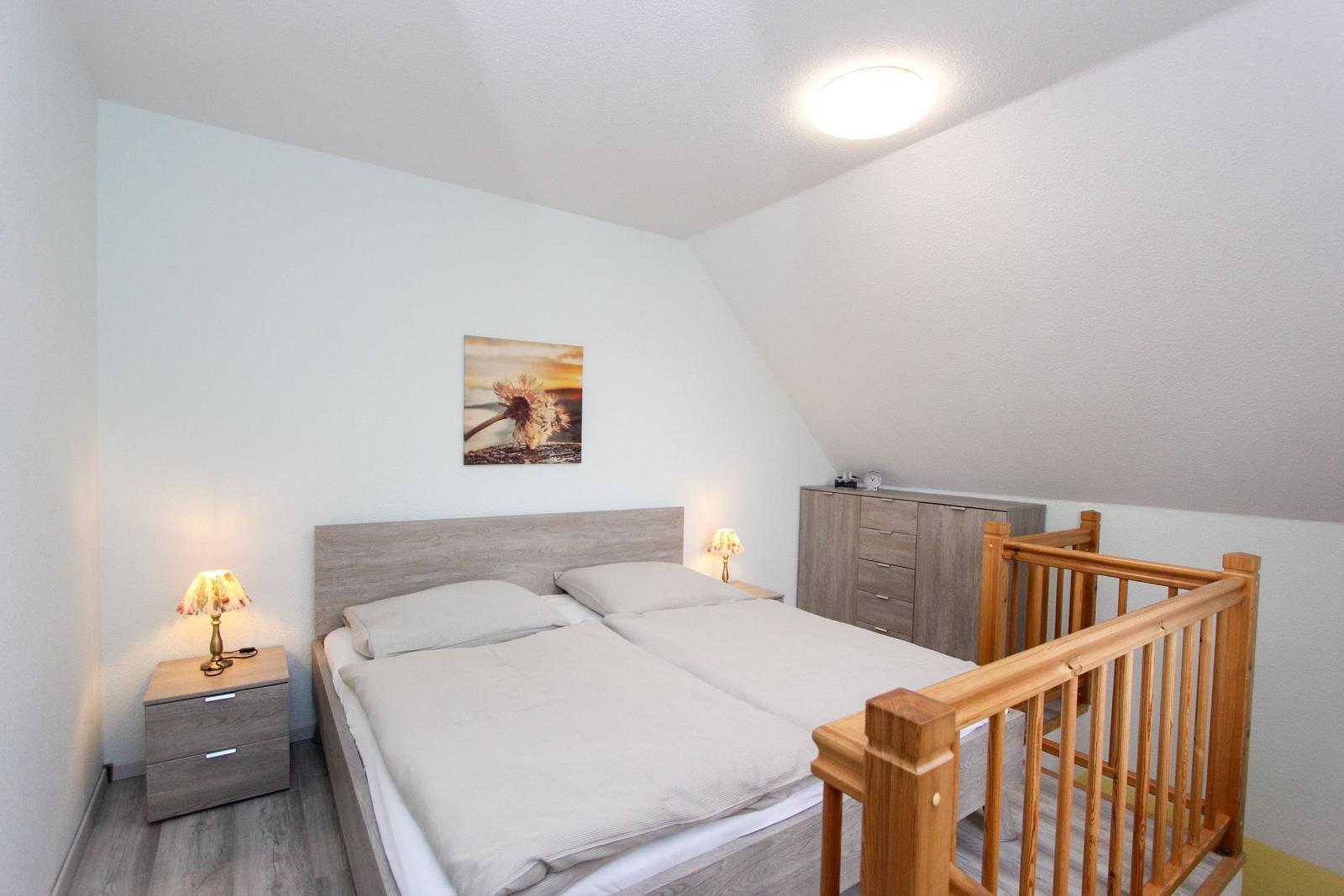 Schlafzimmer mit Doppelbett, Nachttischen und Kleiderschrank unter schrägem Dach.