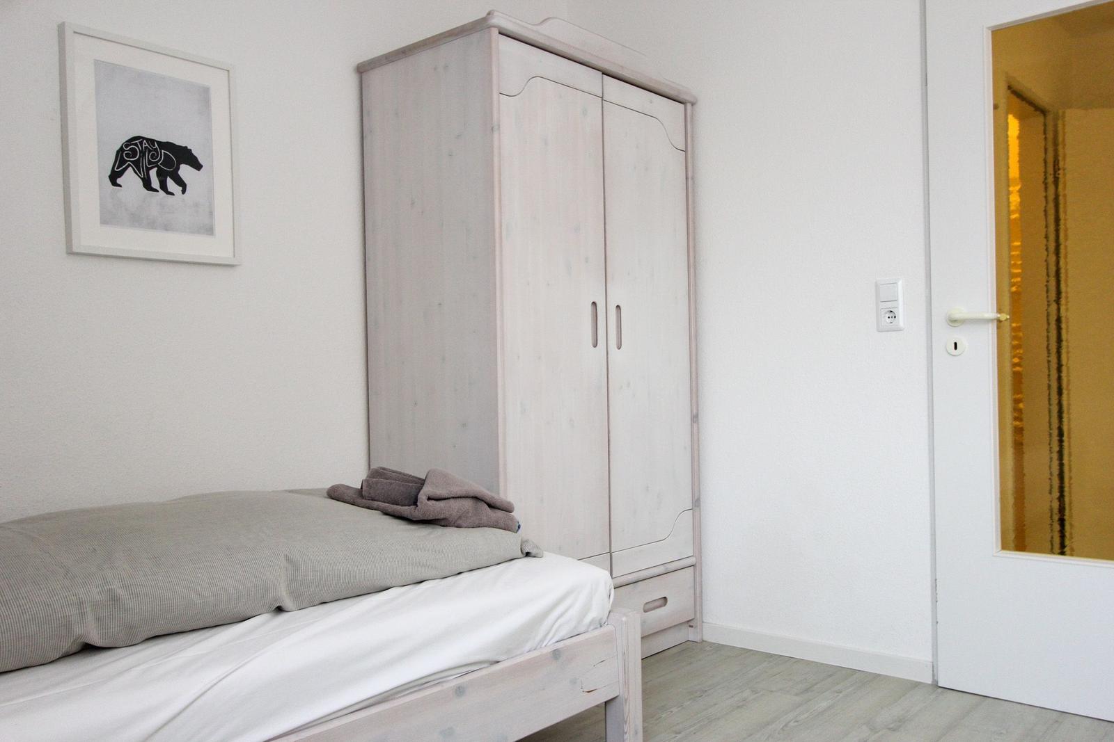 Schlafzimmer mit Bett, Kleiderschrank und Wandbild