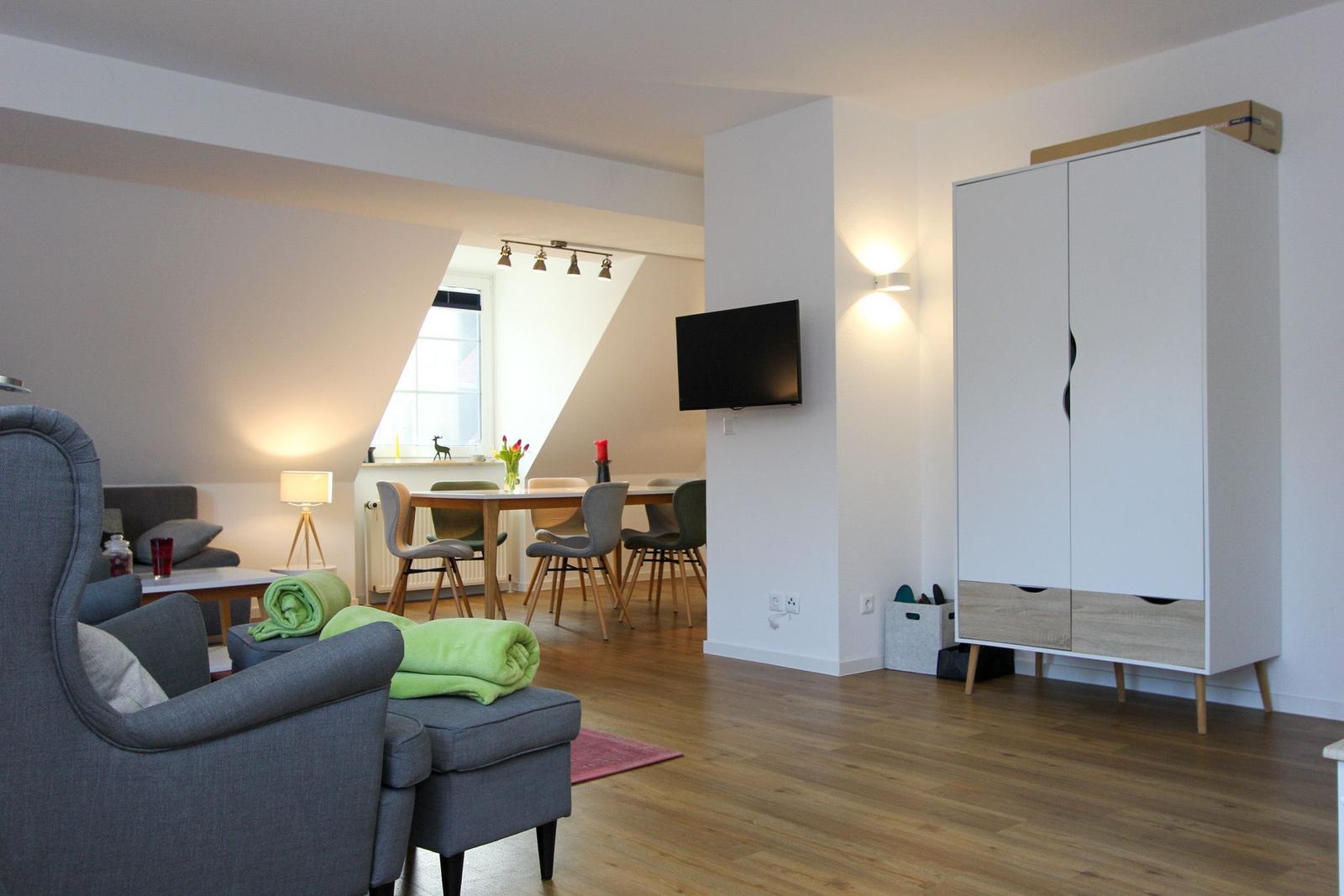 Wohnbereich mit Sitzgruppe, Esstisch und Kleiderschrank. Holzboden und Dachschrägen.