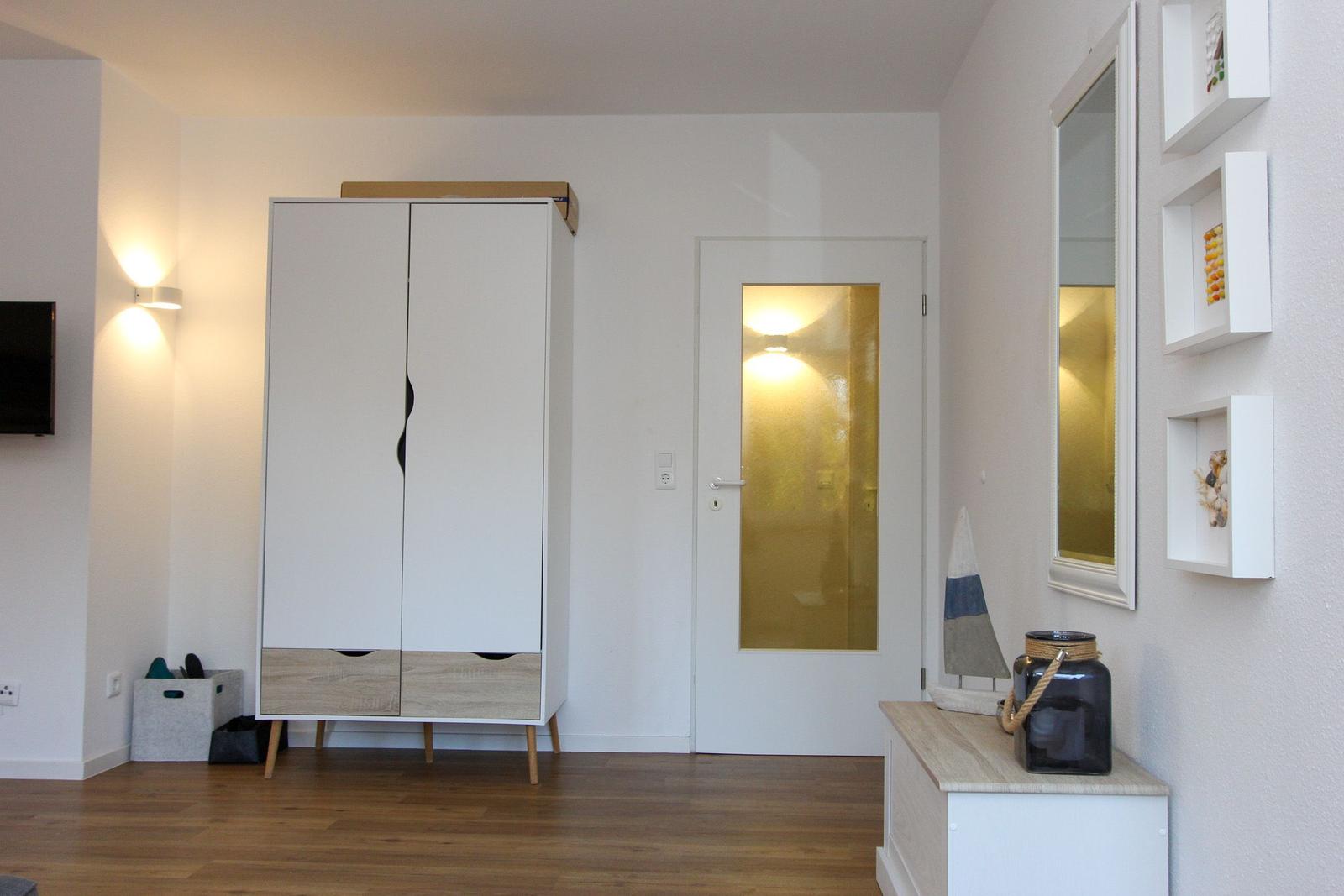 Helle Eingangshalle mit Kleiderschrank, Tür und Wandregalen.