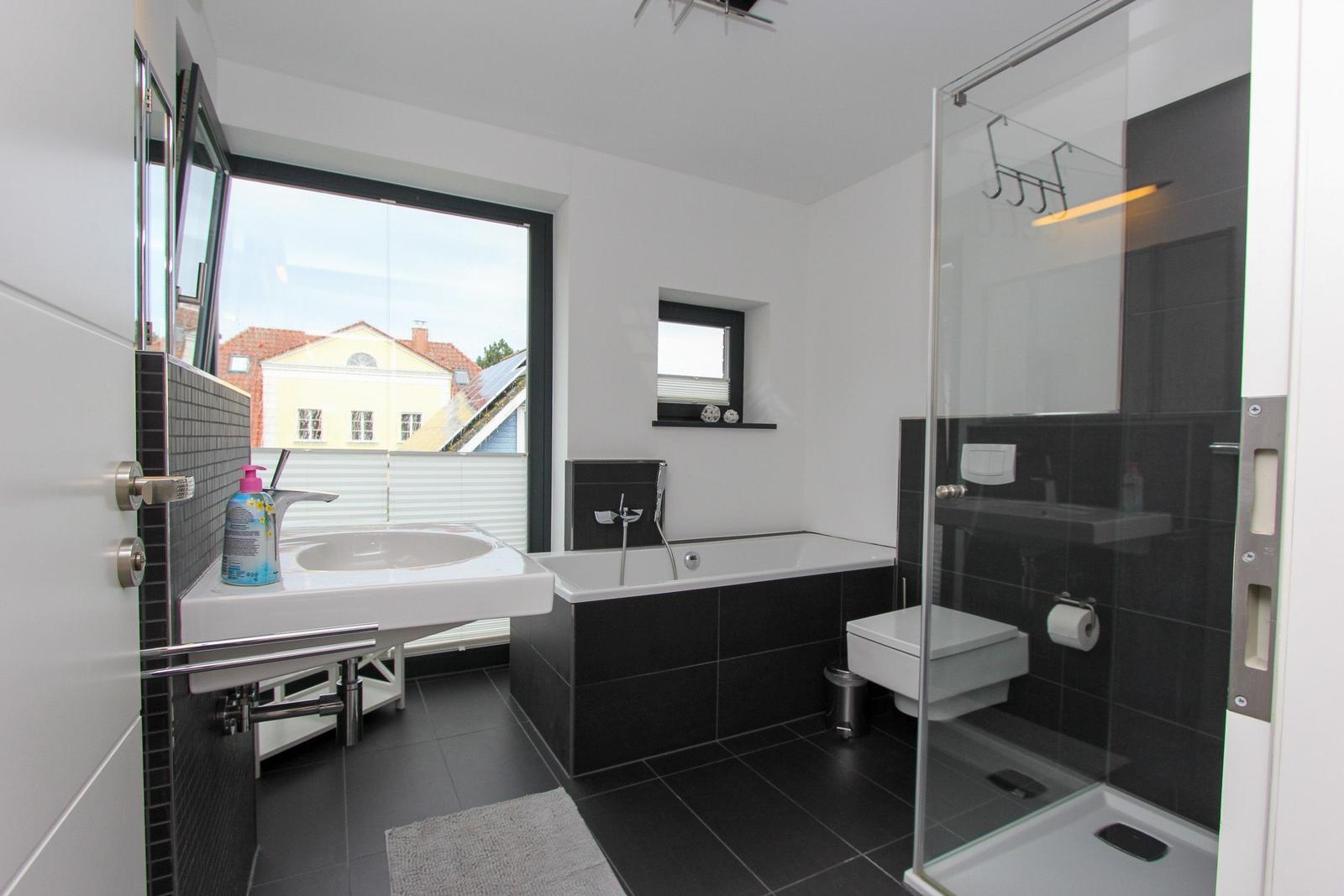 Badezimmer mit Dusche, Badewanne und Fensterblick.