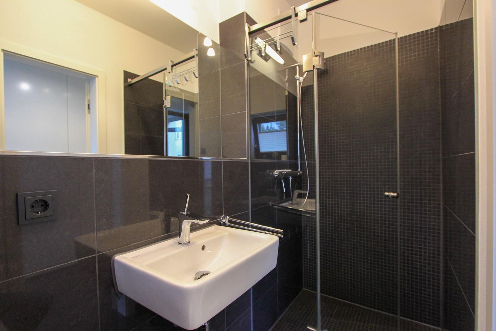 Badezimmer mit Dusche, Waschbecken und Spiegel
