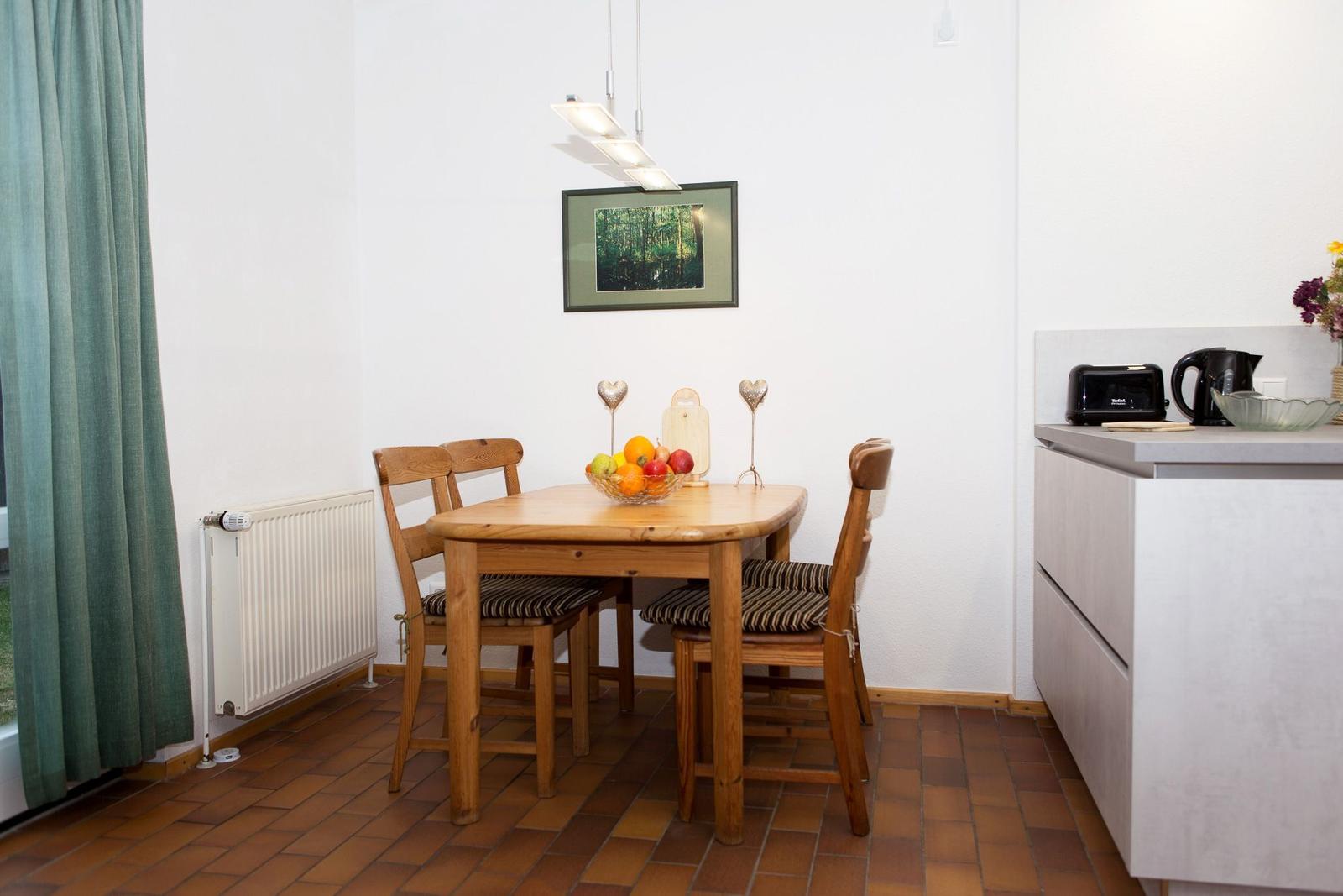 Essbereich mit Holztisch, vier Stühlen und Küchenzeile