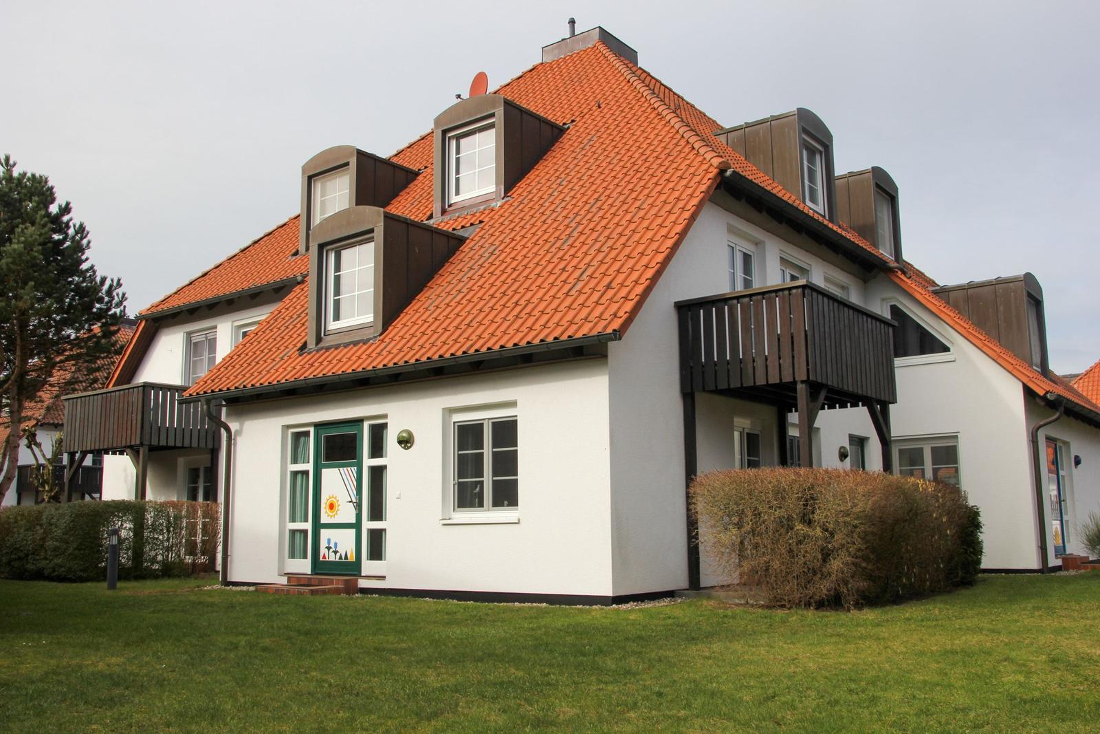 Haus mit rotem Ziegeldach, weißen Wänden und Holzveranda.