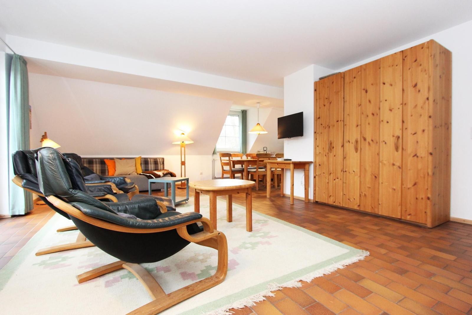 Wohnbereich mit Ledersessel, Sofa, Esstisch und Holzschrank.