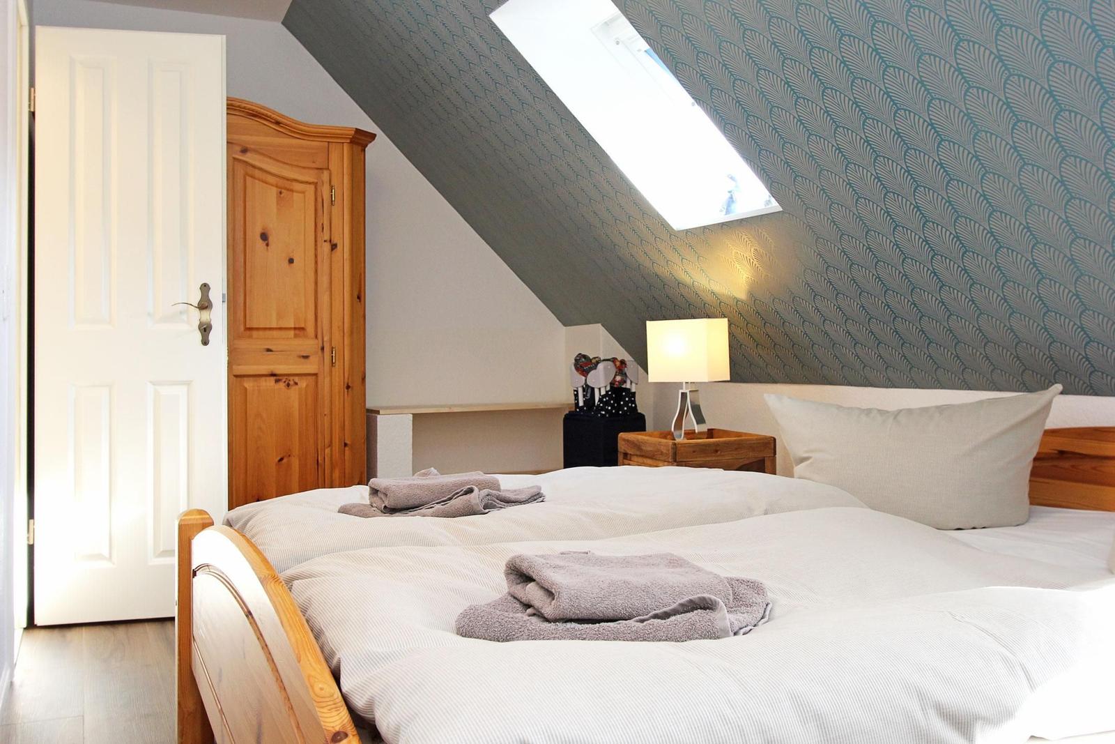 Schlafzimmer mit Dachschrägen, Bett, Nachttisch und Schrank.