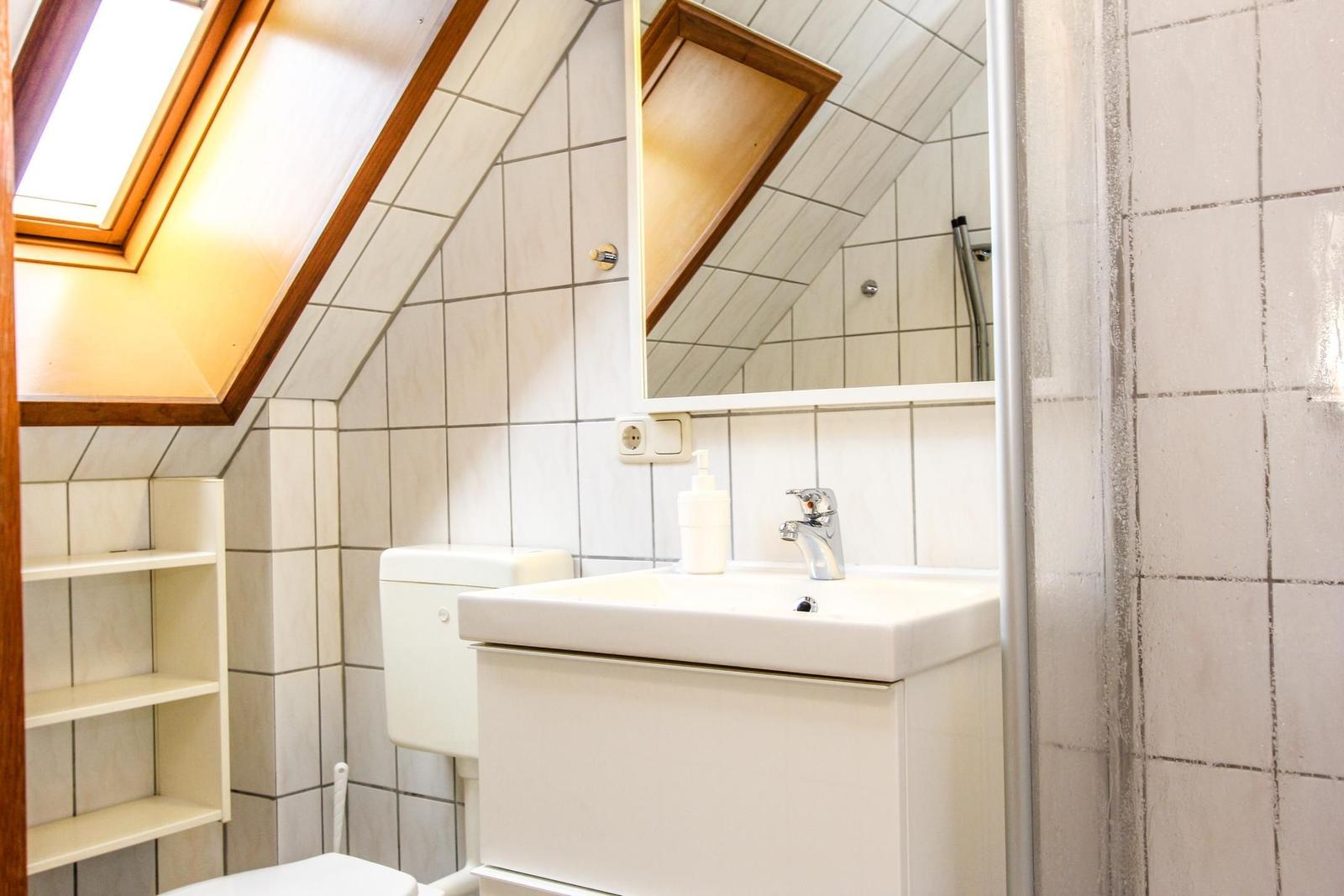 Badezimmer mit Dachschrägen, Waschbecken, Spiegel und Dusche