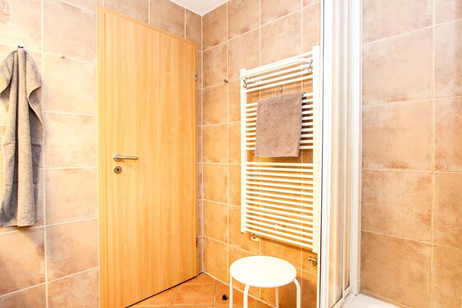Badezimmer mit Holztür, Handtuchhalter und Heizkörper.