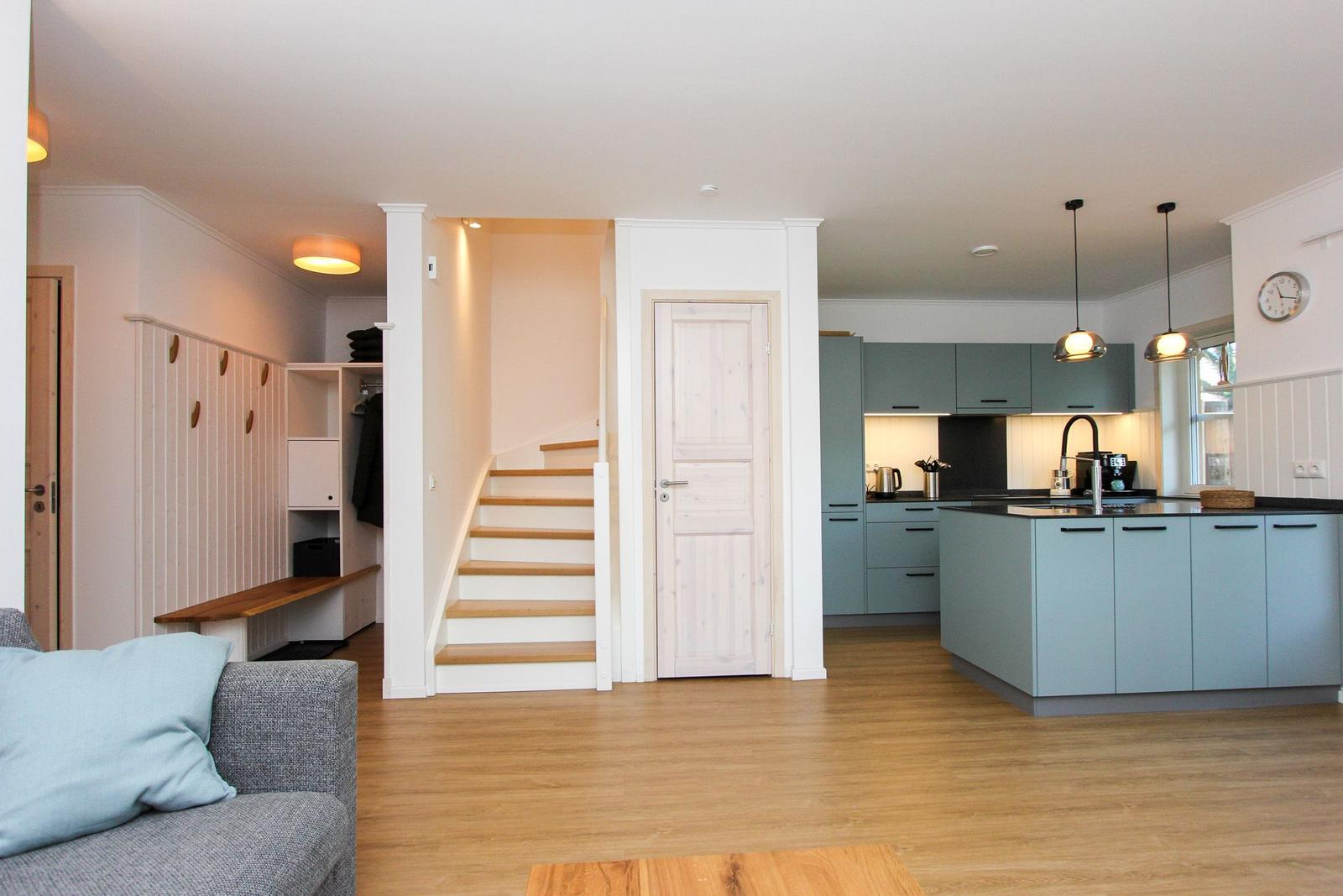 Wohnung mit Küche, Treppenhaus und Schlafzimmer. Holzboden und blaue Küchenmöbel.