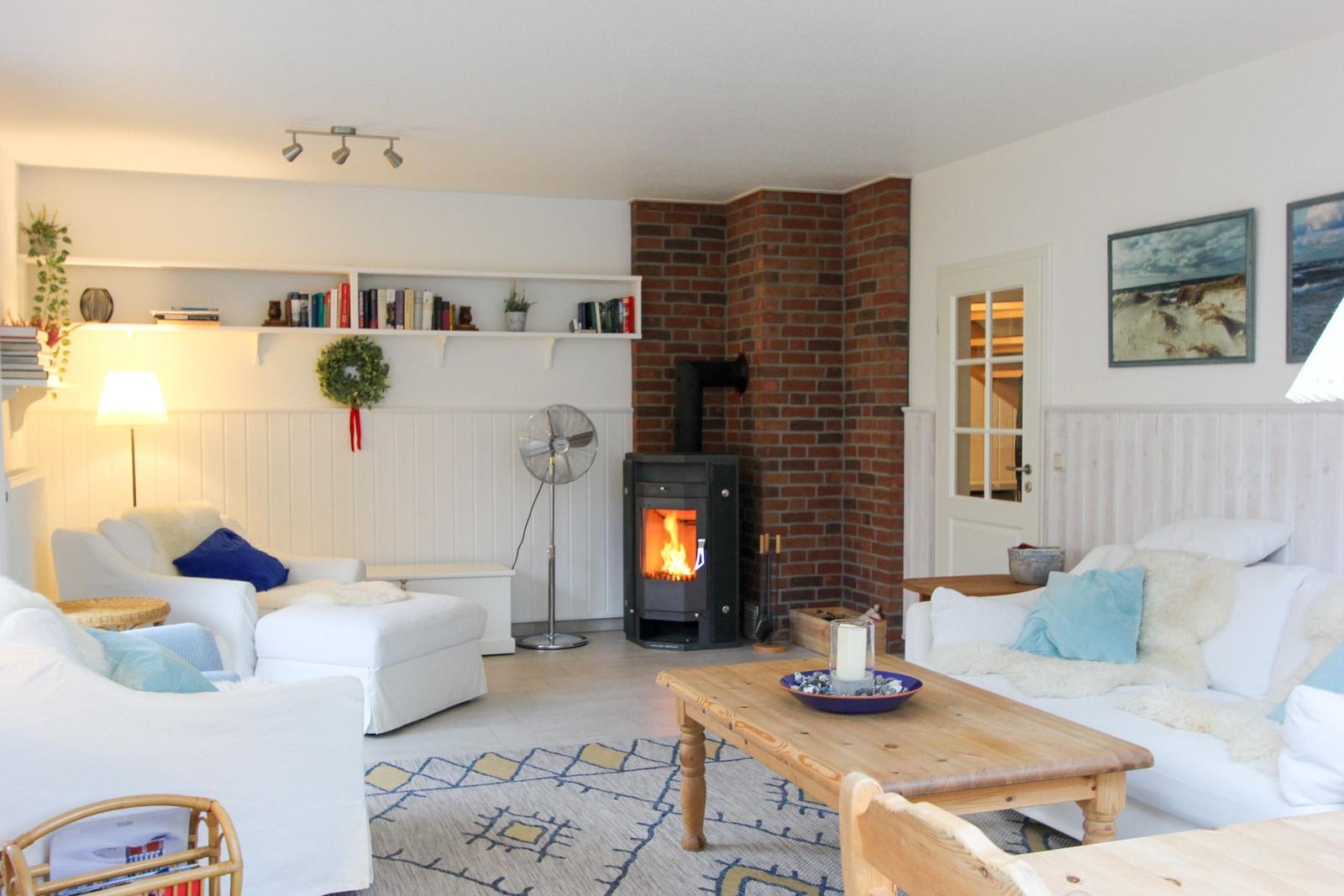 Wohnzimmer mit Kamin, weißen Sofas und Holztisch.