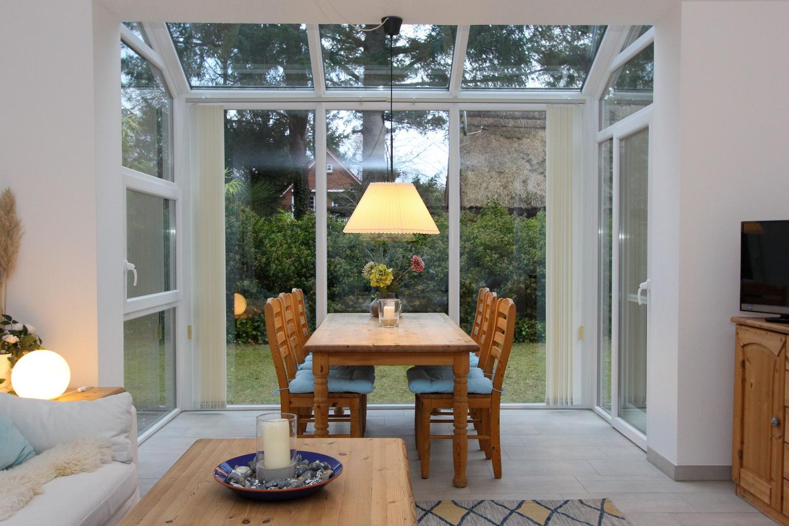 Esszimmer mit Holztisch, Stühlen und Blick auf den Garten.