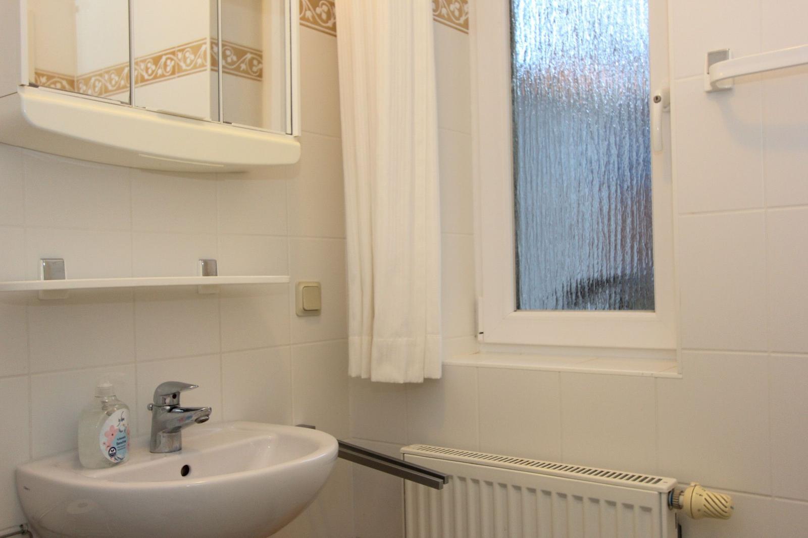Bad mit Waschbecken, Spiegel und Fenster mit Glastüren