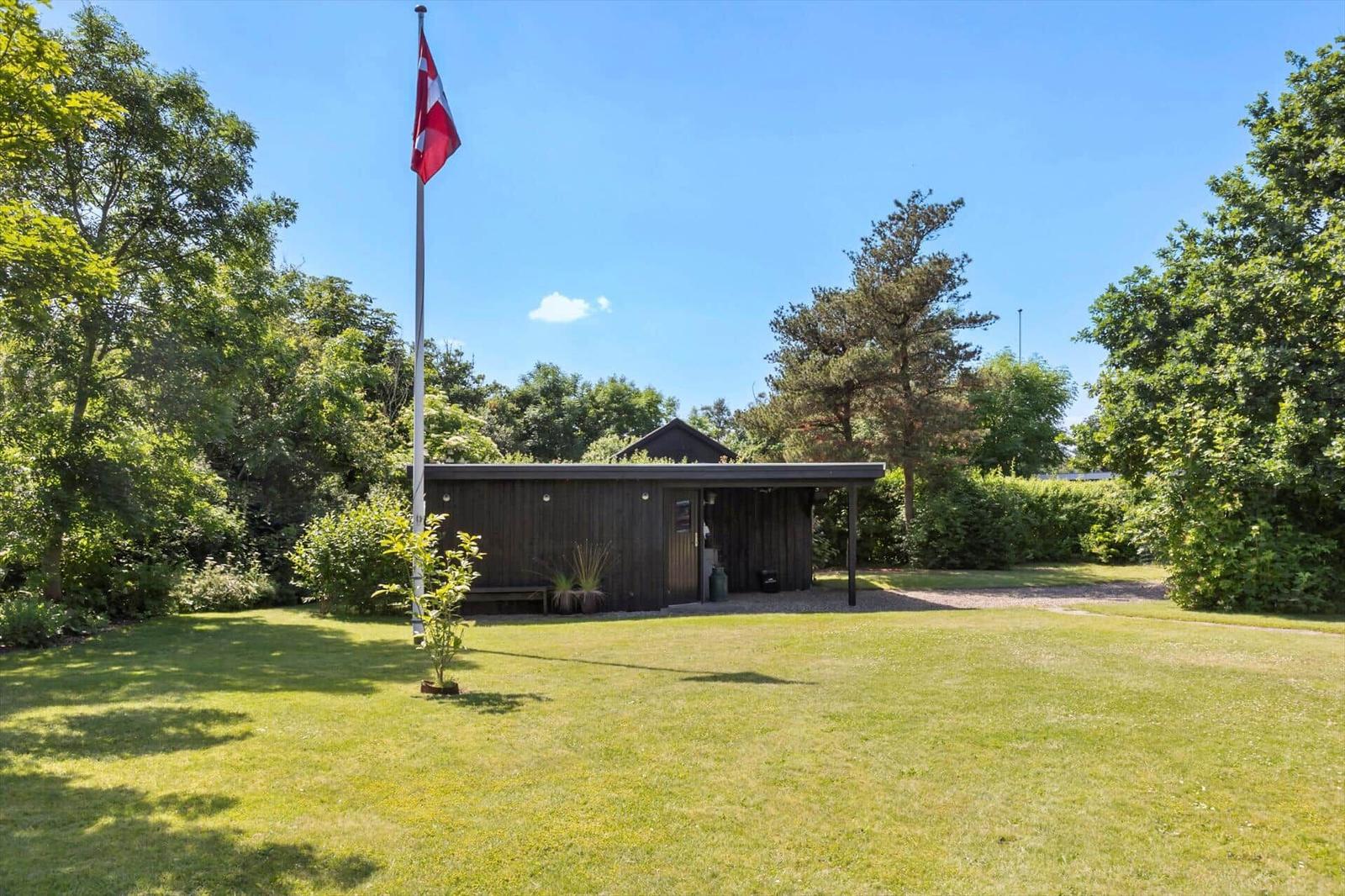 Holzhütte mit Flagge auf grünem Rasen umgeben von Bäumen