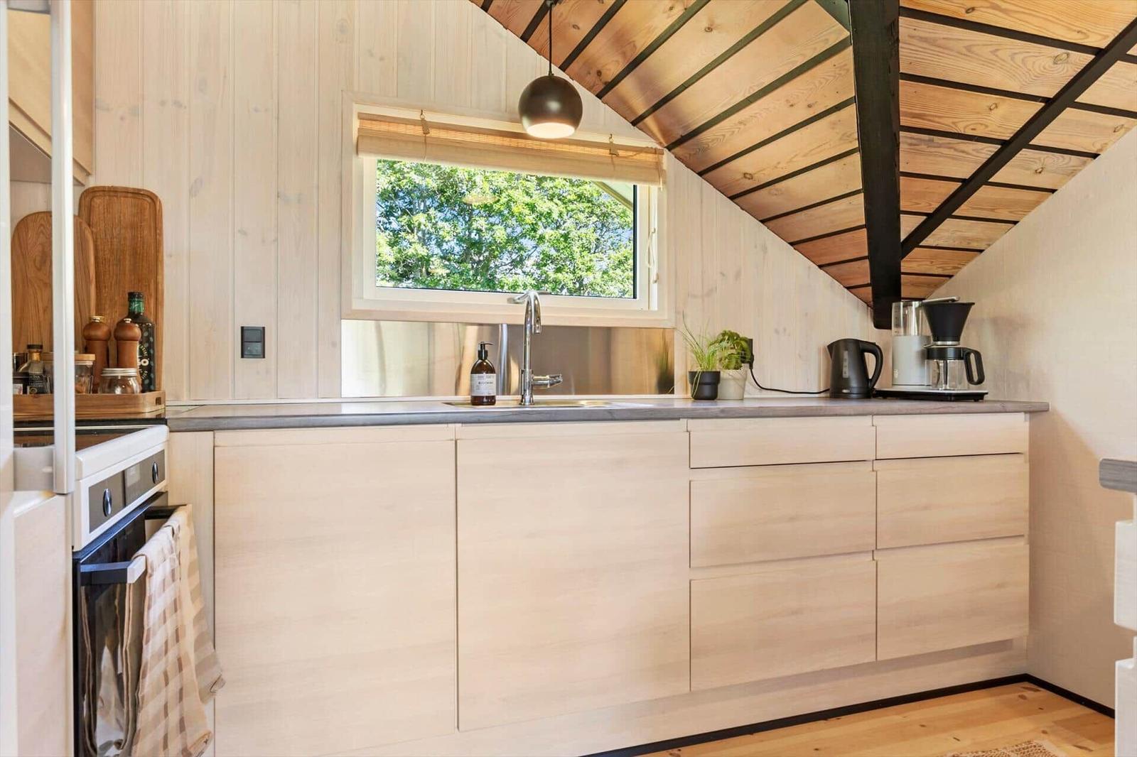 Küche mit Holzwand, Fenster und Küchenspüle.