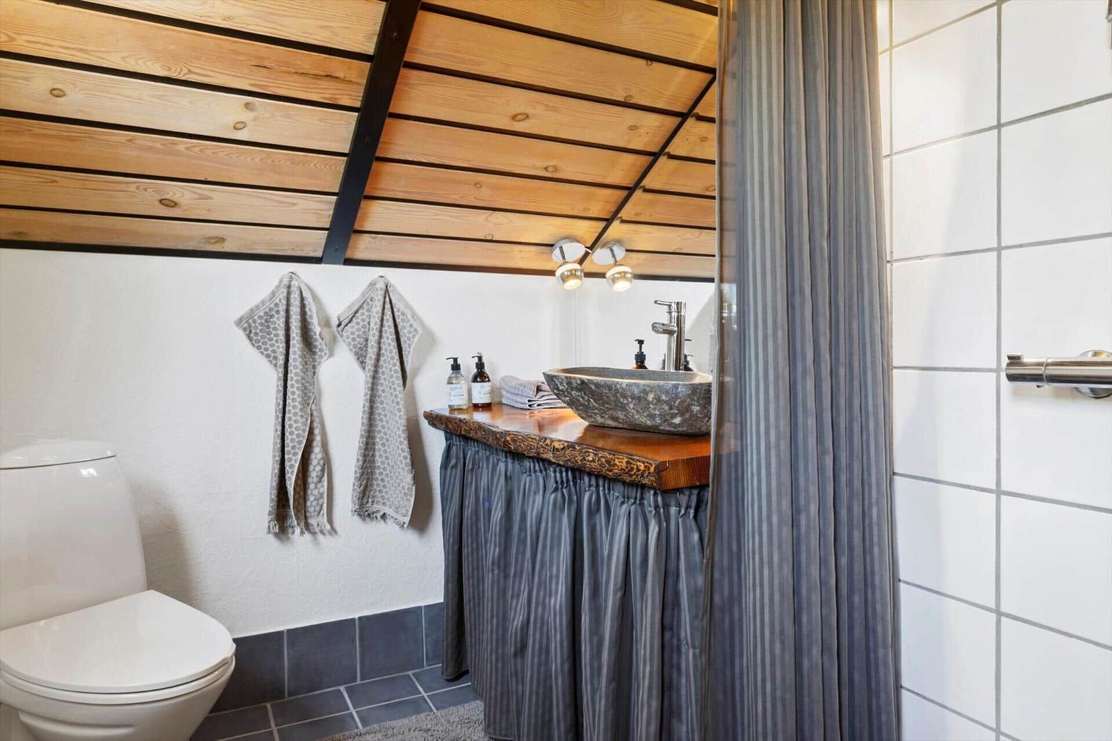 Badezimmer mit Holzdecke, Waschtisch und Toilette