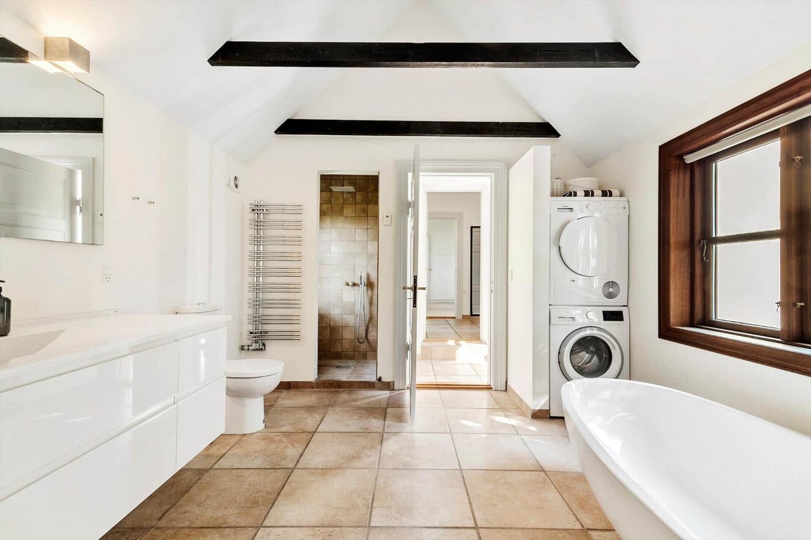 Badezimmer mit Badewanne, Waschmaschine, Dusche und Toilette