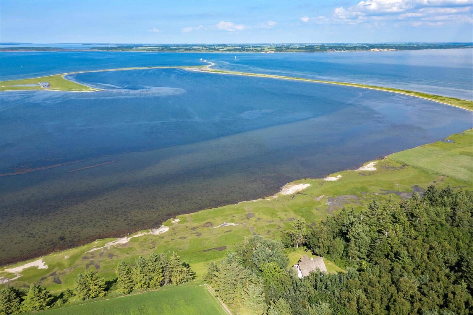 Haus am Ufer mit Blick auf das Meer und eine Insel im Hintergrund.