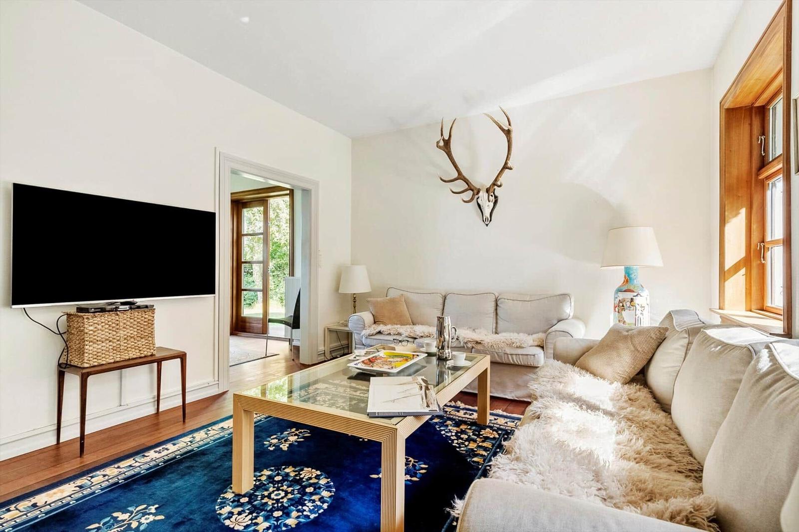 Wohnzimmer mit Sofa, Glas-Tisch und Wanddekoration