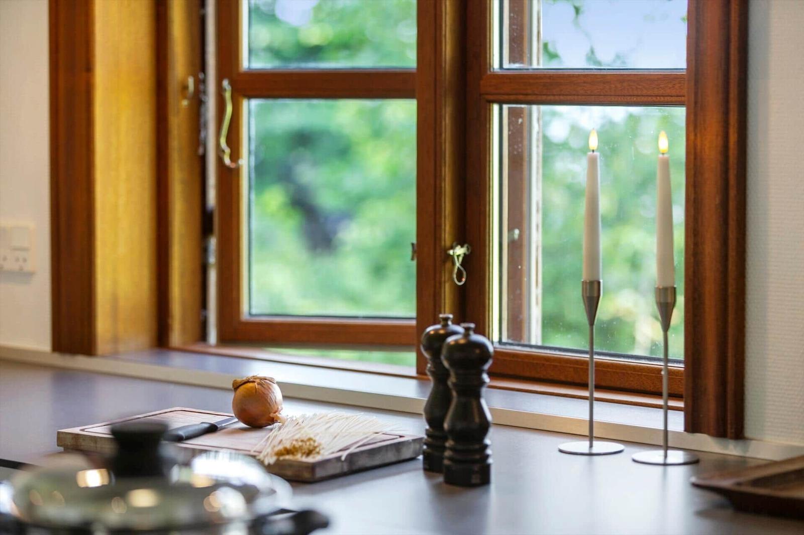 Küchenfenster mit Kerzen, Gewürzstreuer und Zutaten auf Arbeitsfläche.